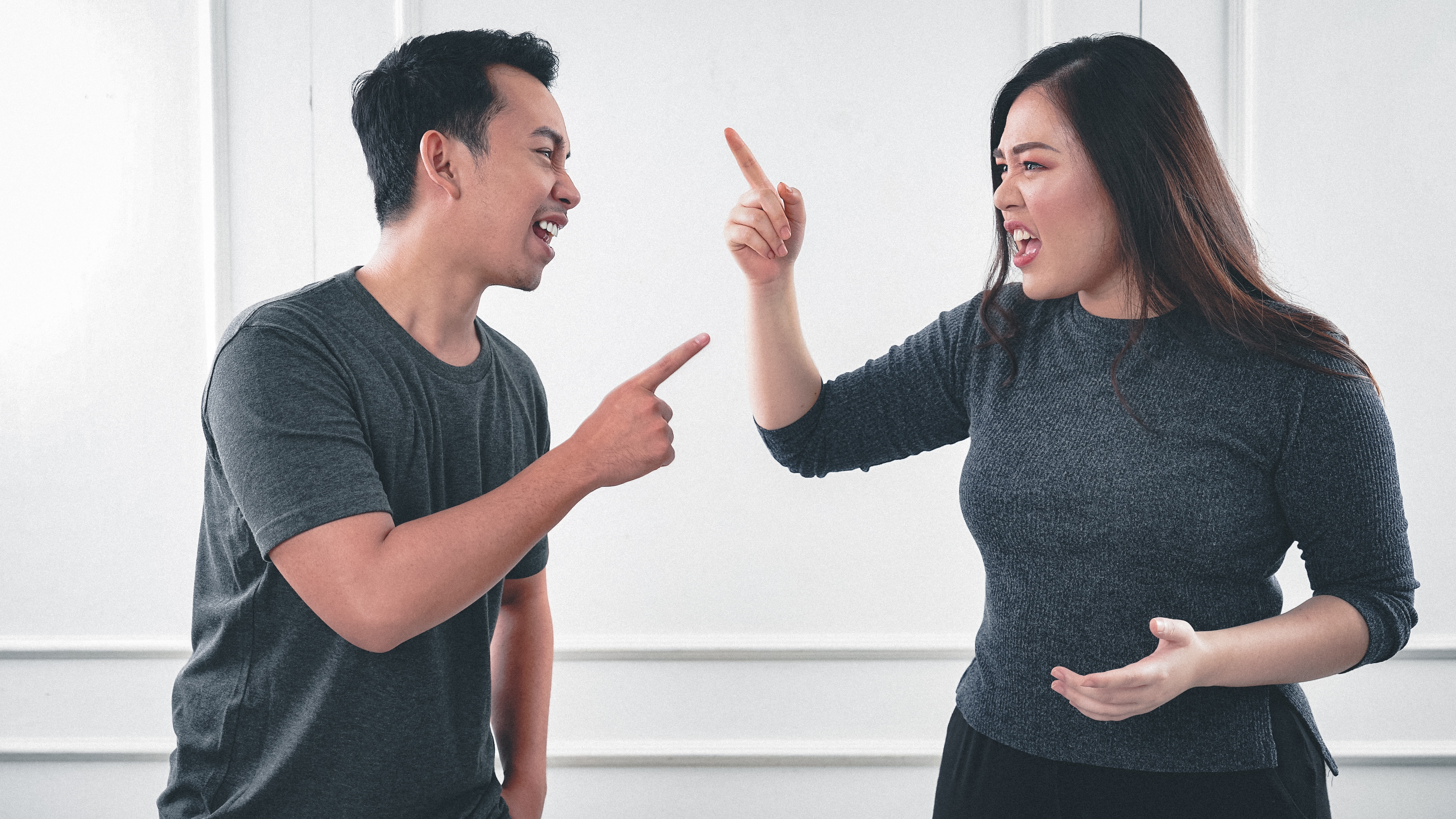 A photo of a man and a woman pointing at each other | Source: Unsplash