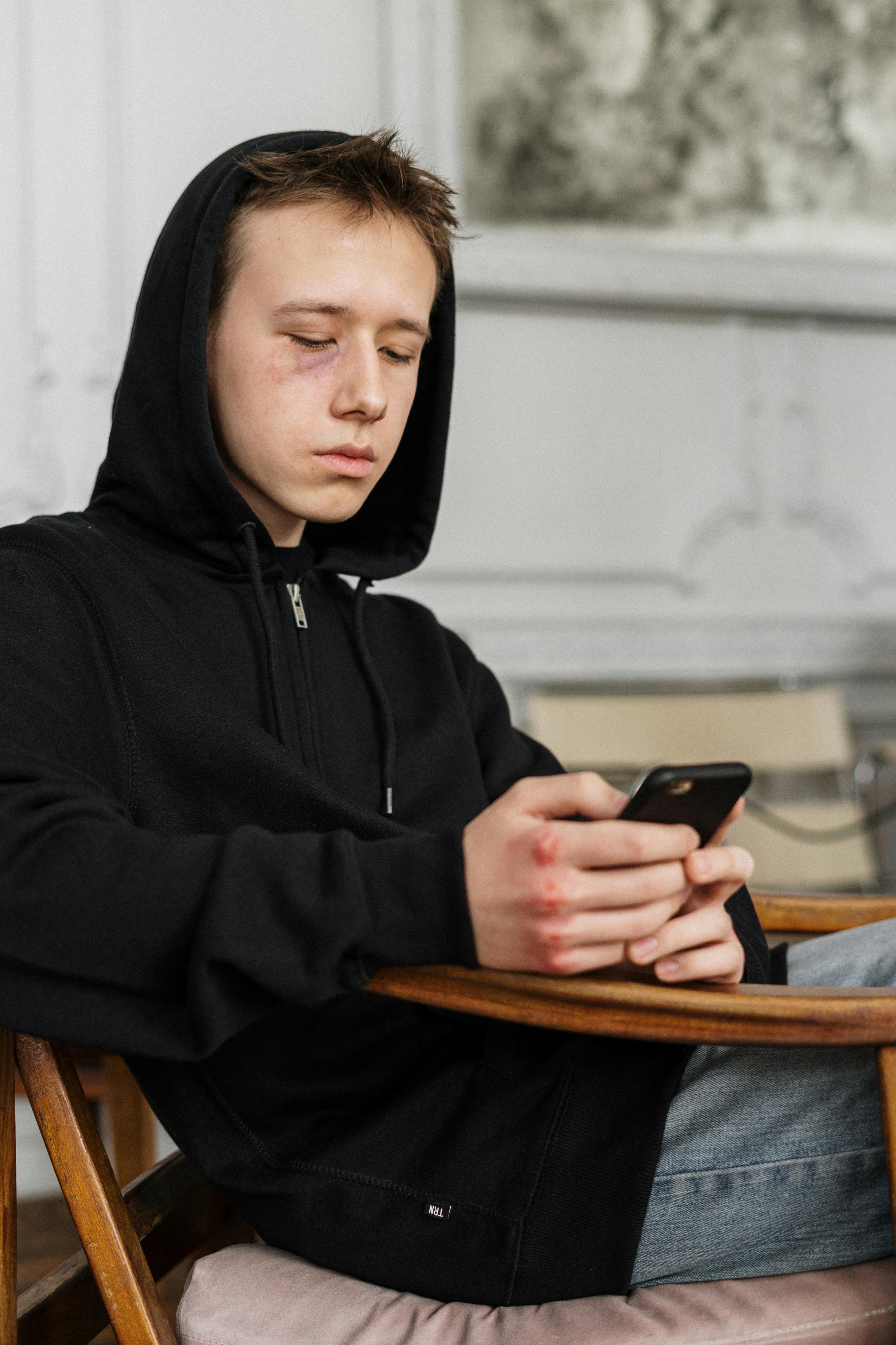 A teenage boy holding a phone | Source: Pexels