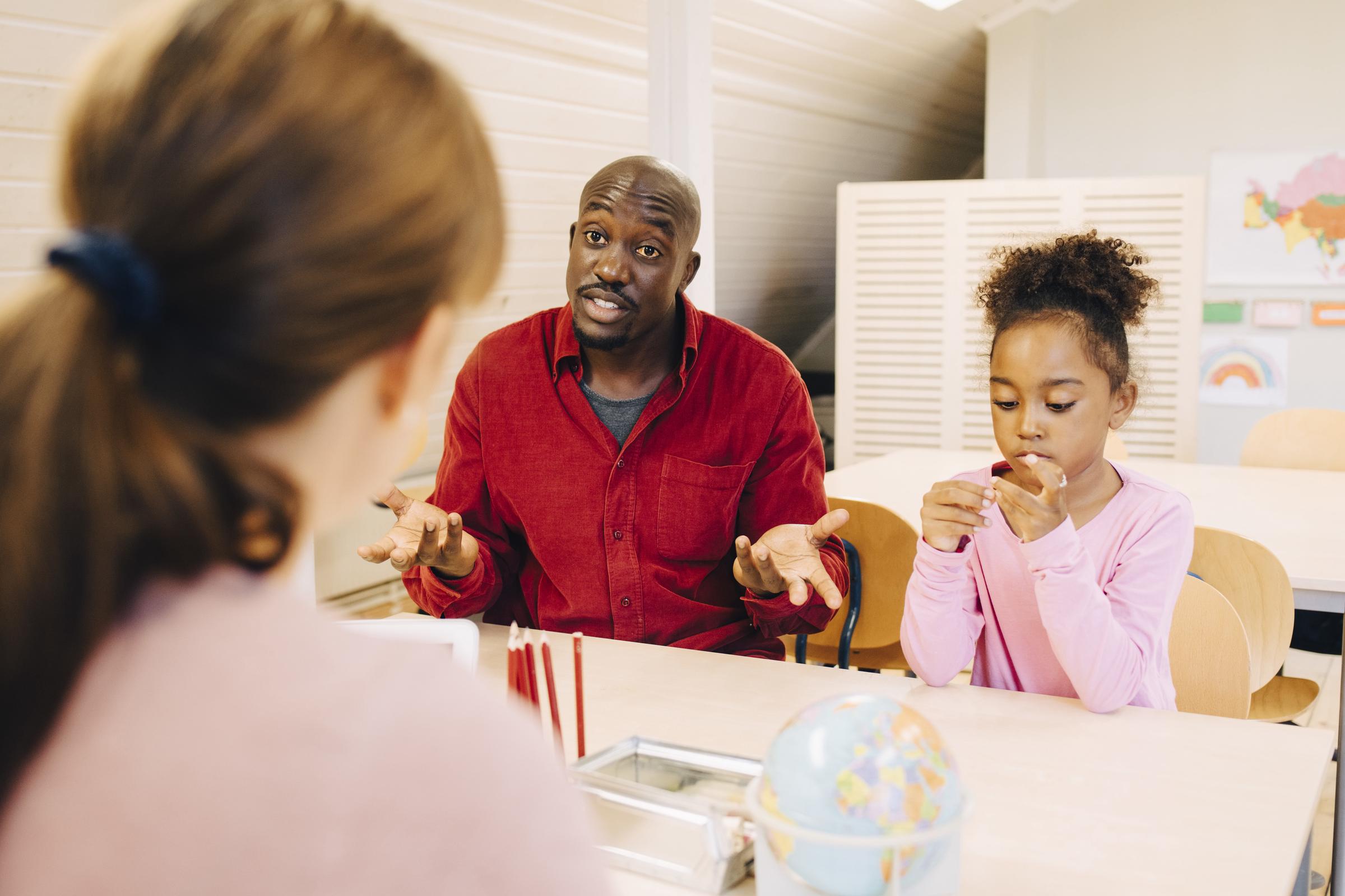 A man sitting with child talking to teacher | Source: Getty Images