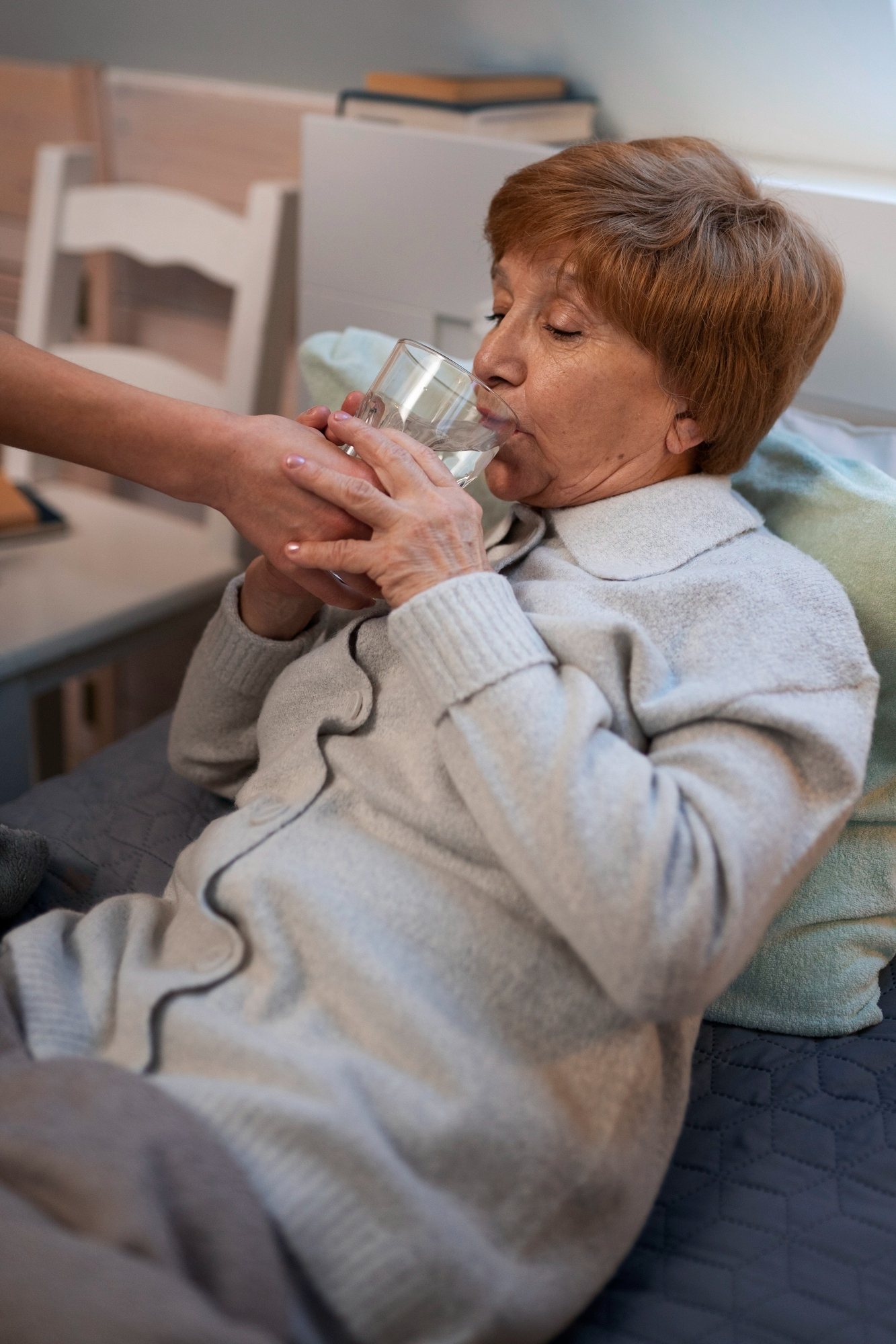 A woman helping an ill middle-aged woman drink water | Source: Freepik