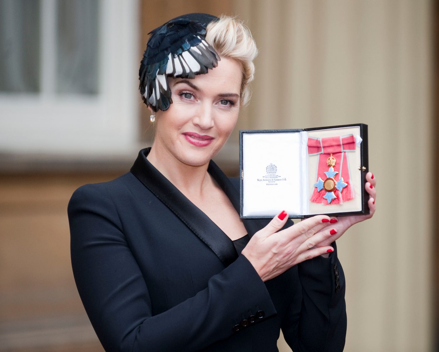 Actress Kate Winslet shows off her 2012 CBE award after an investiture ceremony with Queen Elizabeth II at Buckingham Palace.  |  Photo: Getty Images