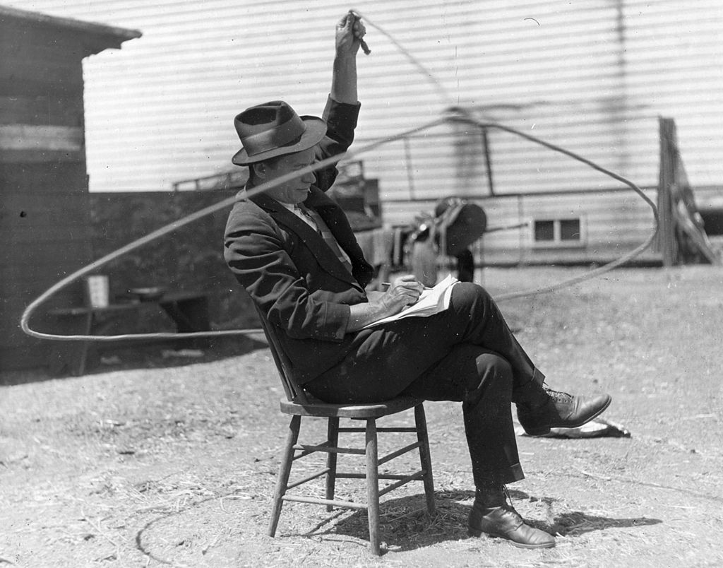 Will Rogers (1879 - 1935), American rustic comedian playing with a lasso whilst writing himself some notes | Photo: Getty Images