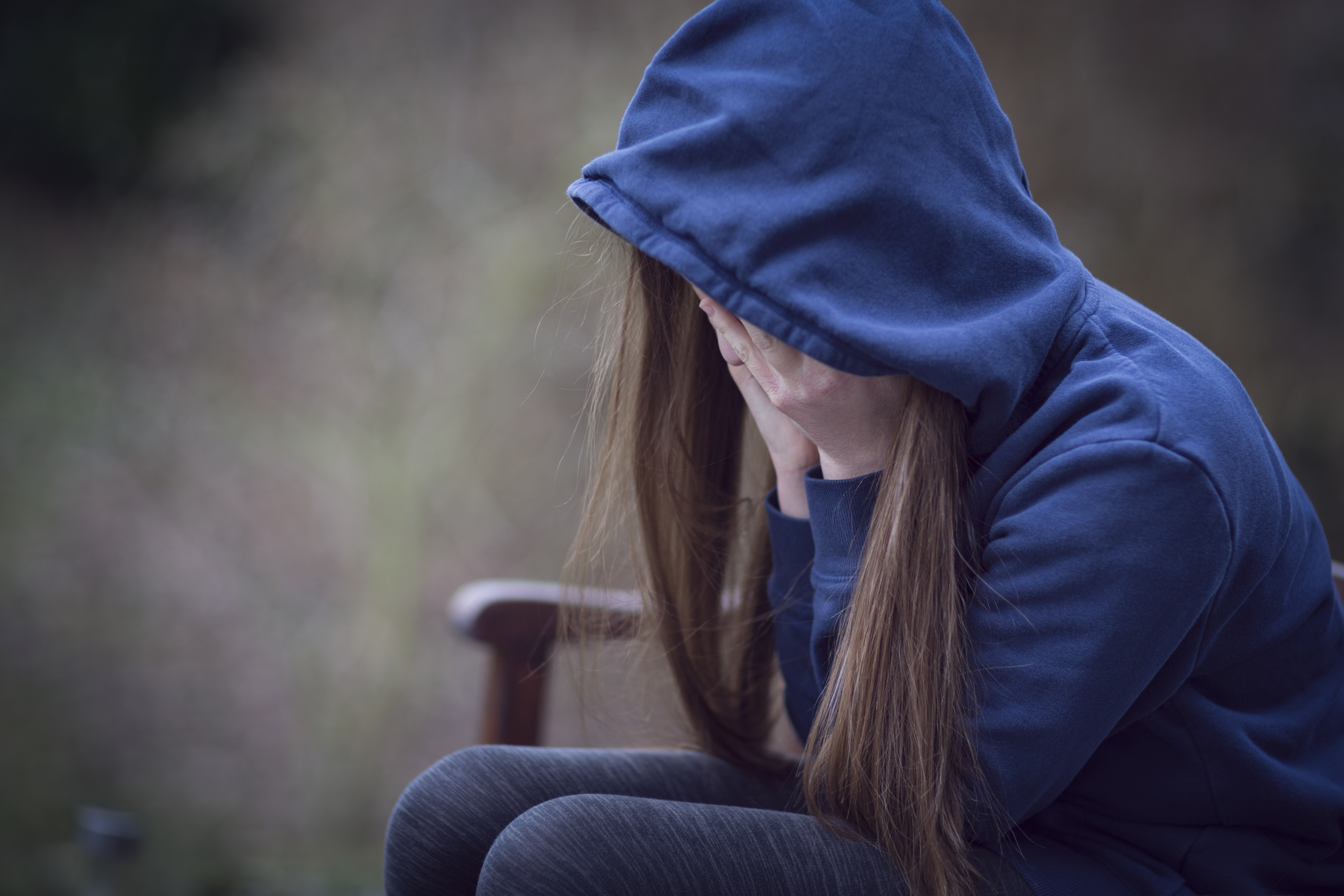 Teenage girl in hooded top, with head in hands in despair | Source: Getty Images