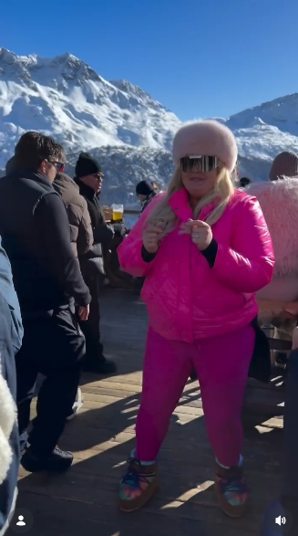 Gemma Collins dances on a wooden terrace surrounded by snow-covered mountains while dressed head to toe in fluorescent pink in a post shared on February 1, 2026. | Source: Instagram/gemmacollins