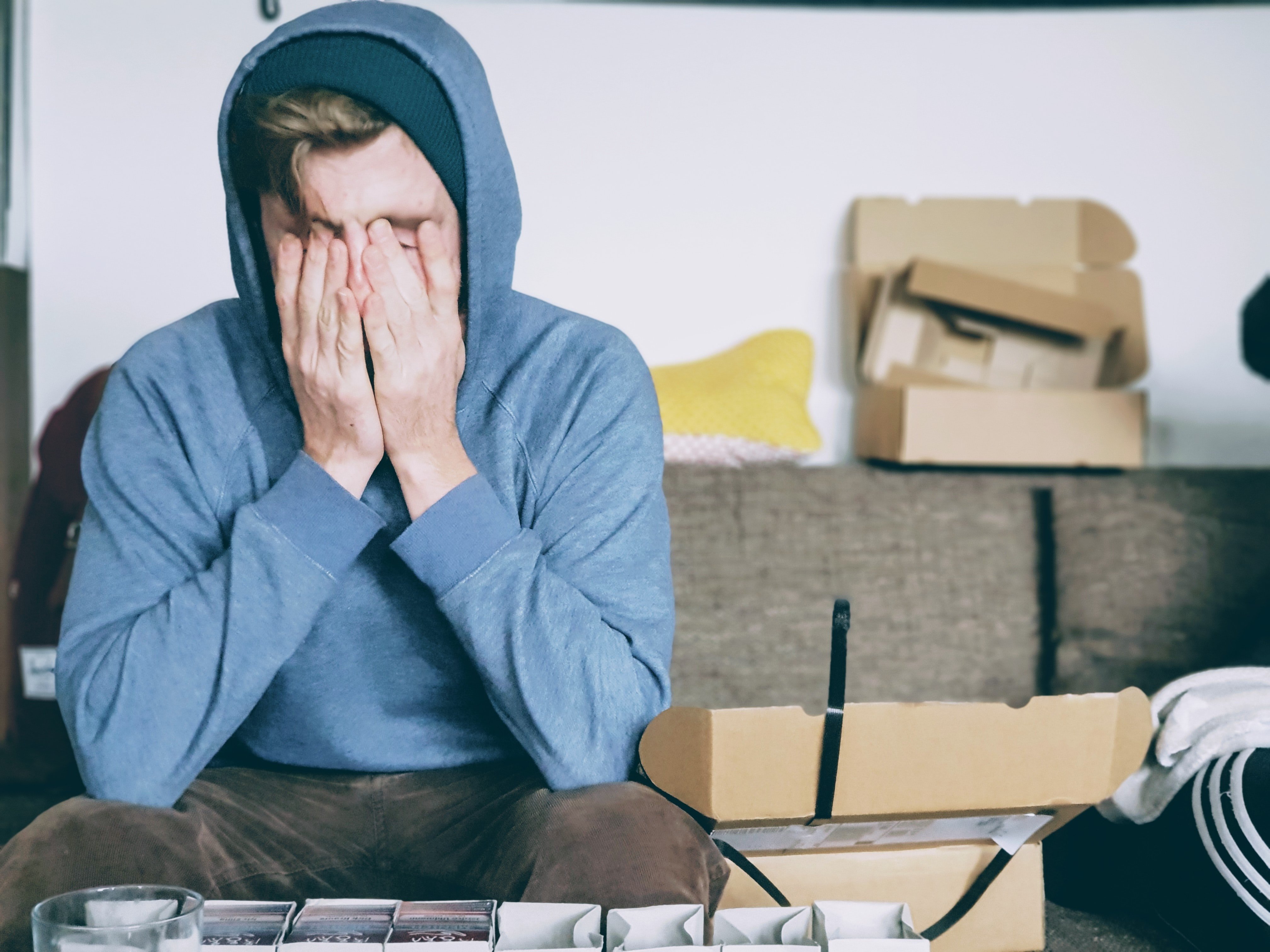 An upset young man sitting with his hands over her eyes | Source: Unsplash