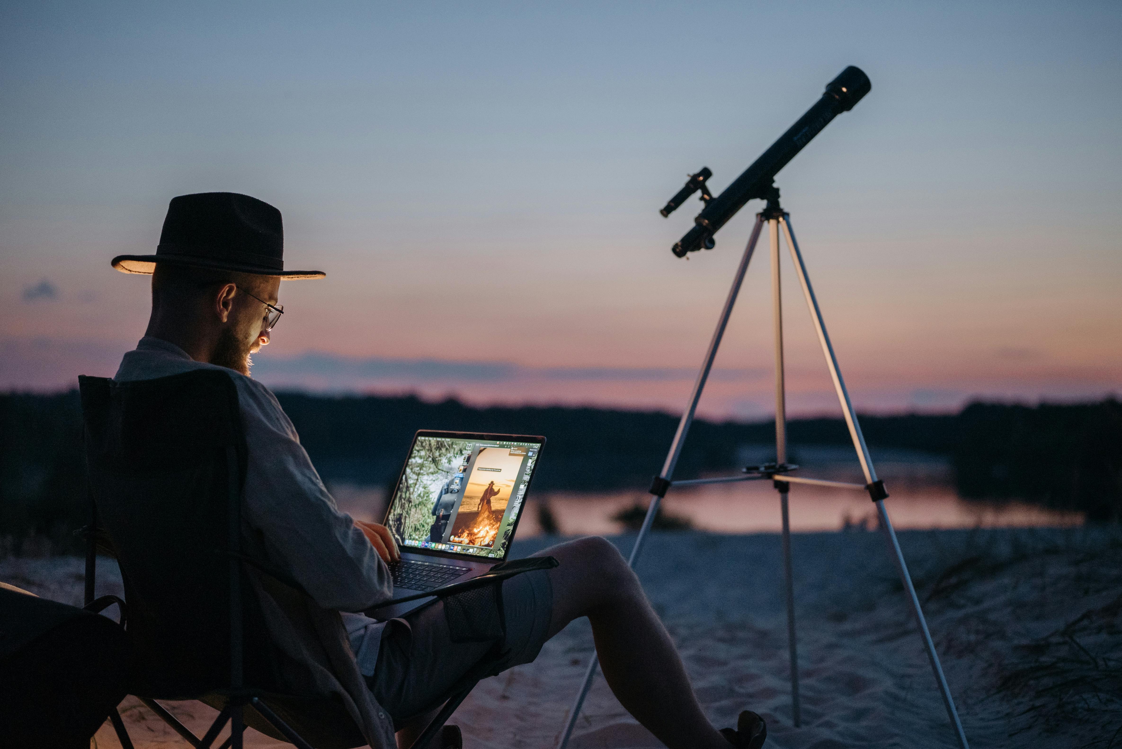 A man outdoors with a telescope set up nearby | Source: Pexels