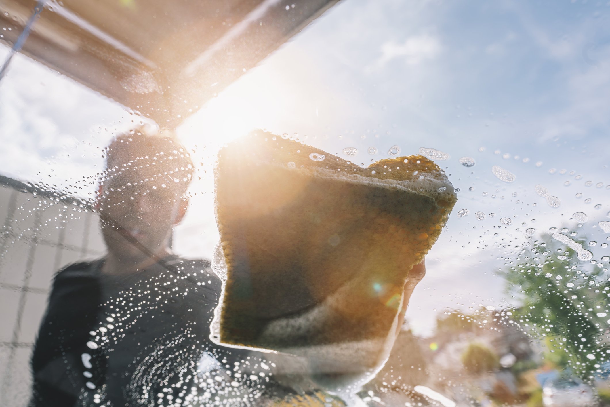 A man washing his car seen through windshield. | Photo: Getty Images