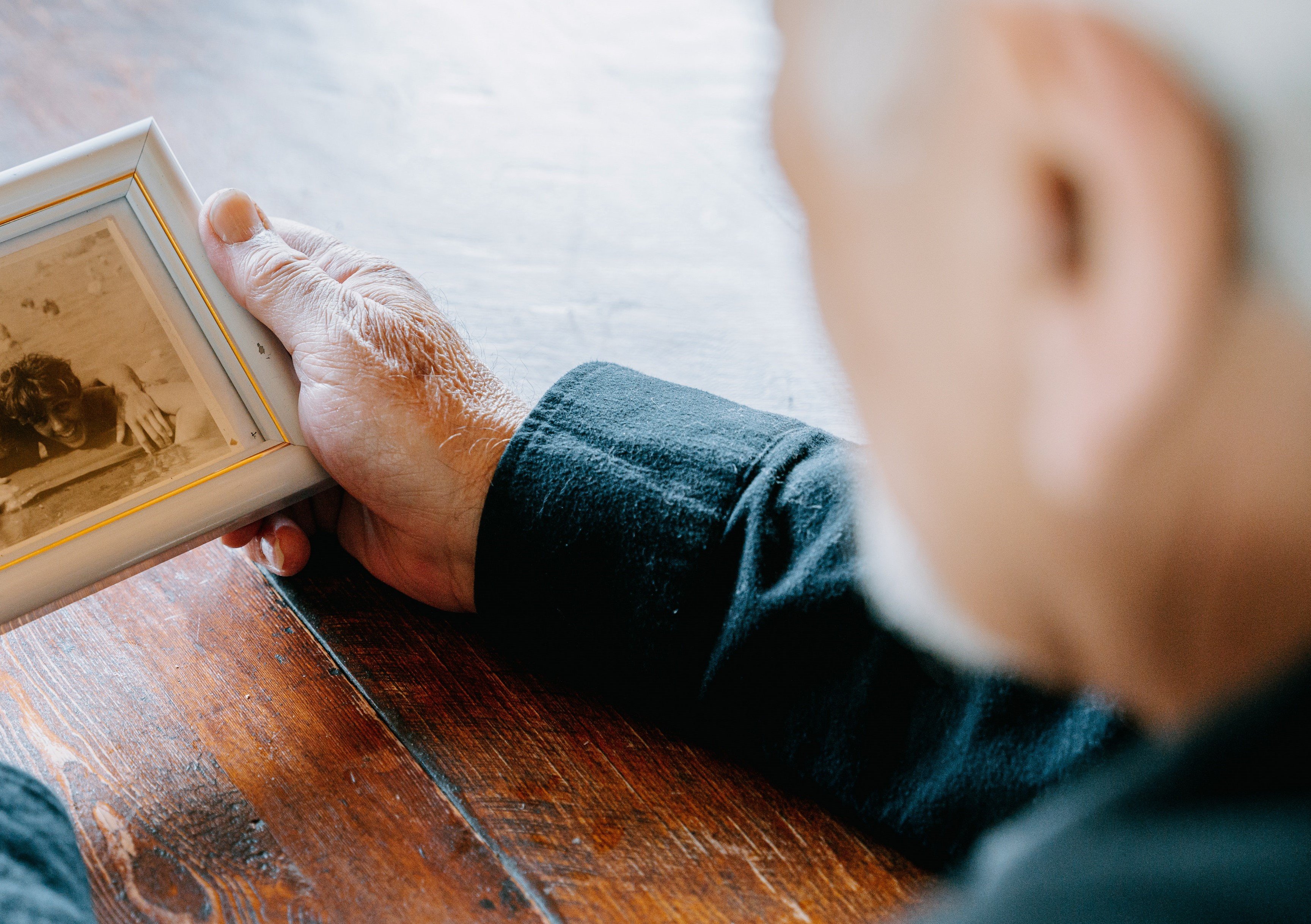 An elderly man holding a picture frame | Source: Pexels