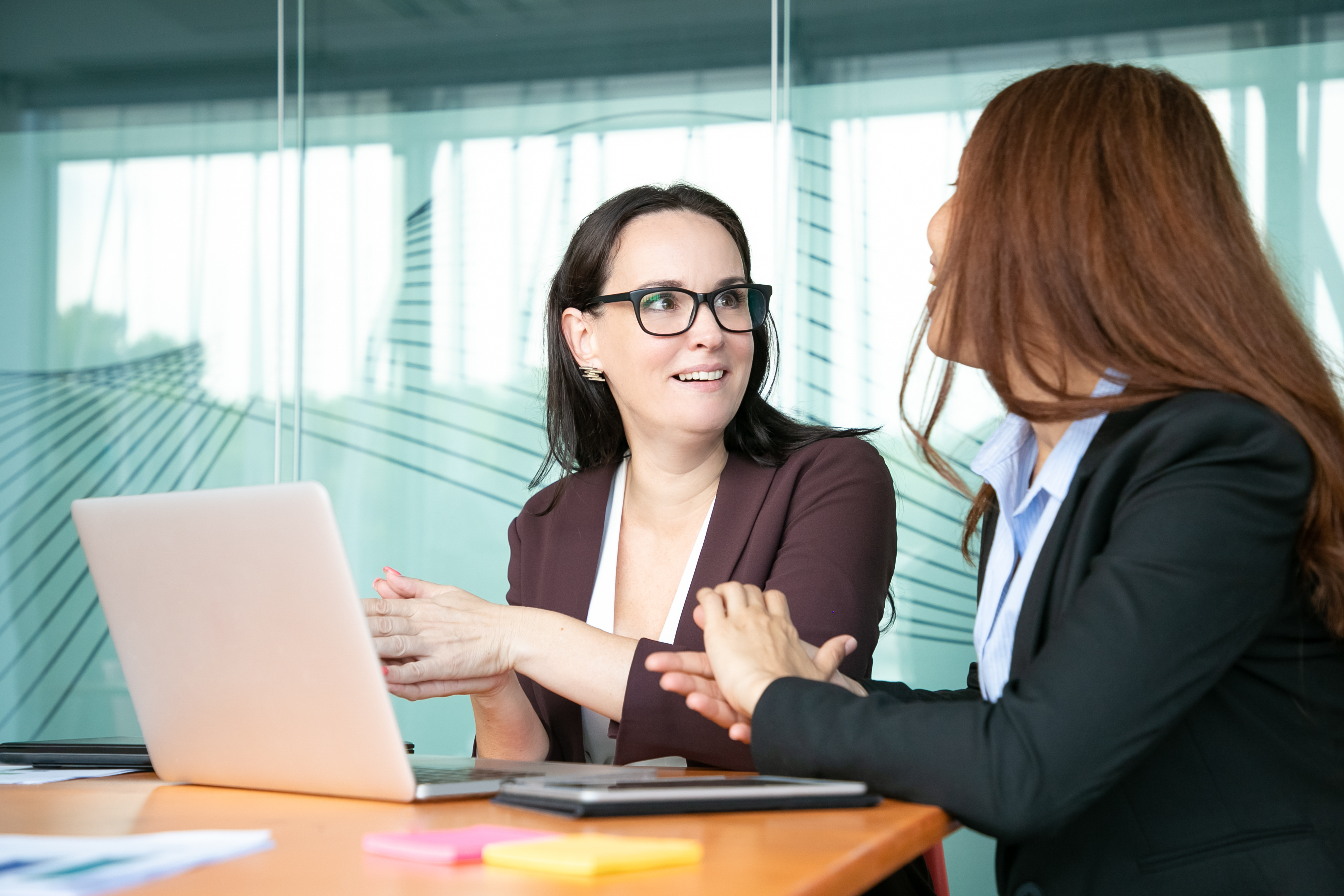 A smiling woman chatting with her co-worker | Source: Freepik