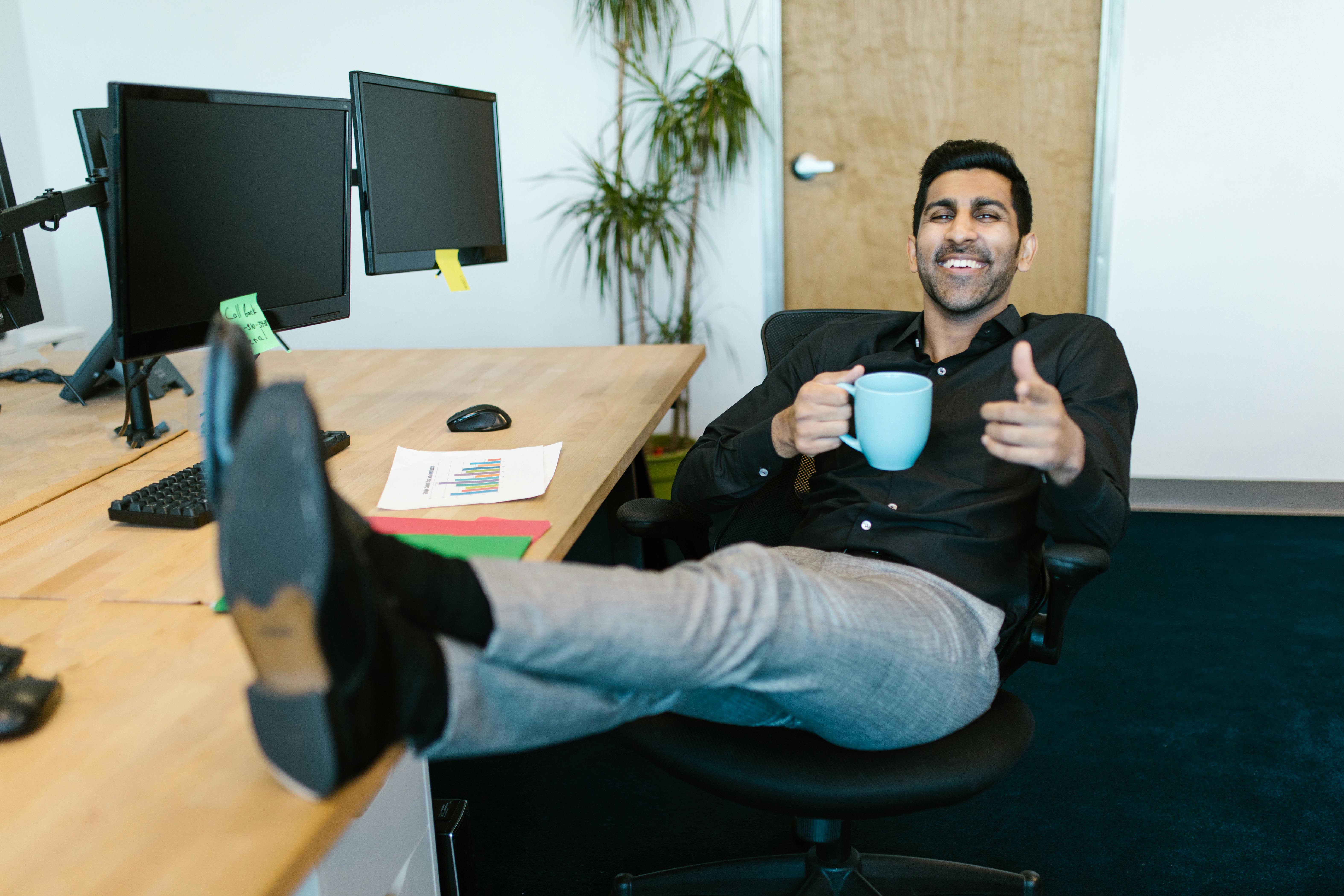 A happy man enjoying a beverage in his office | Source: Pexels