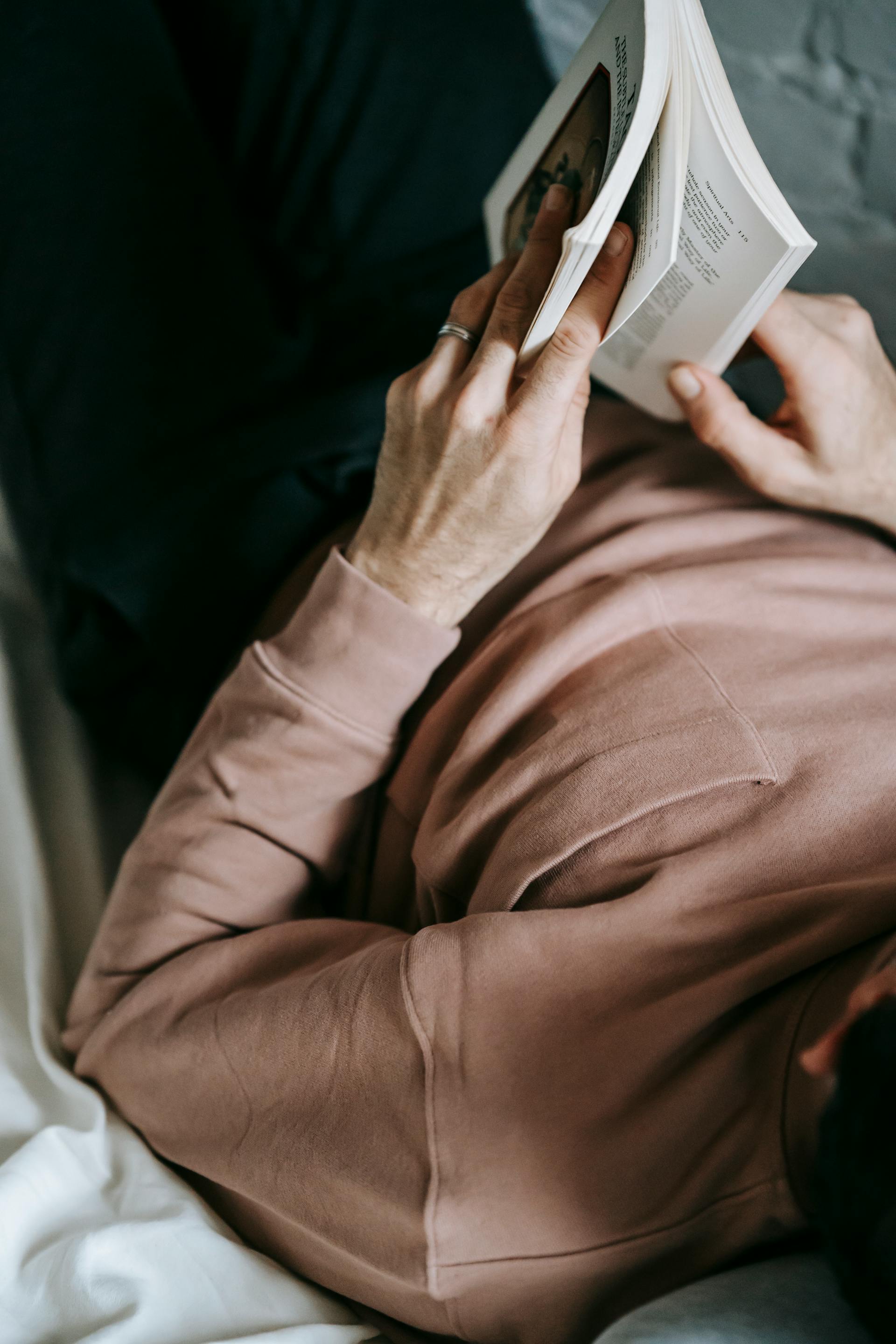 A closeup shot of a man reading a book in bed | Source: Pexels