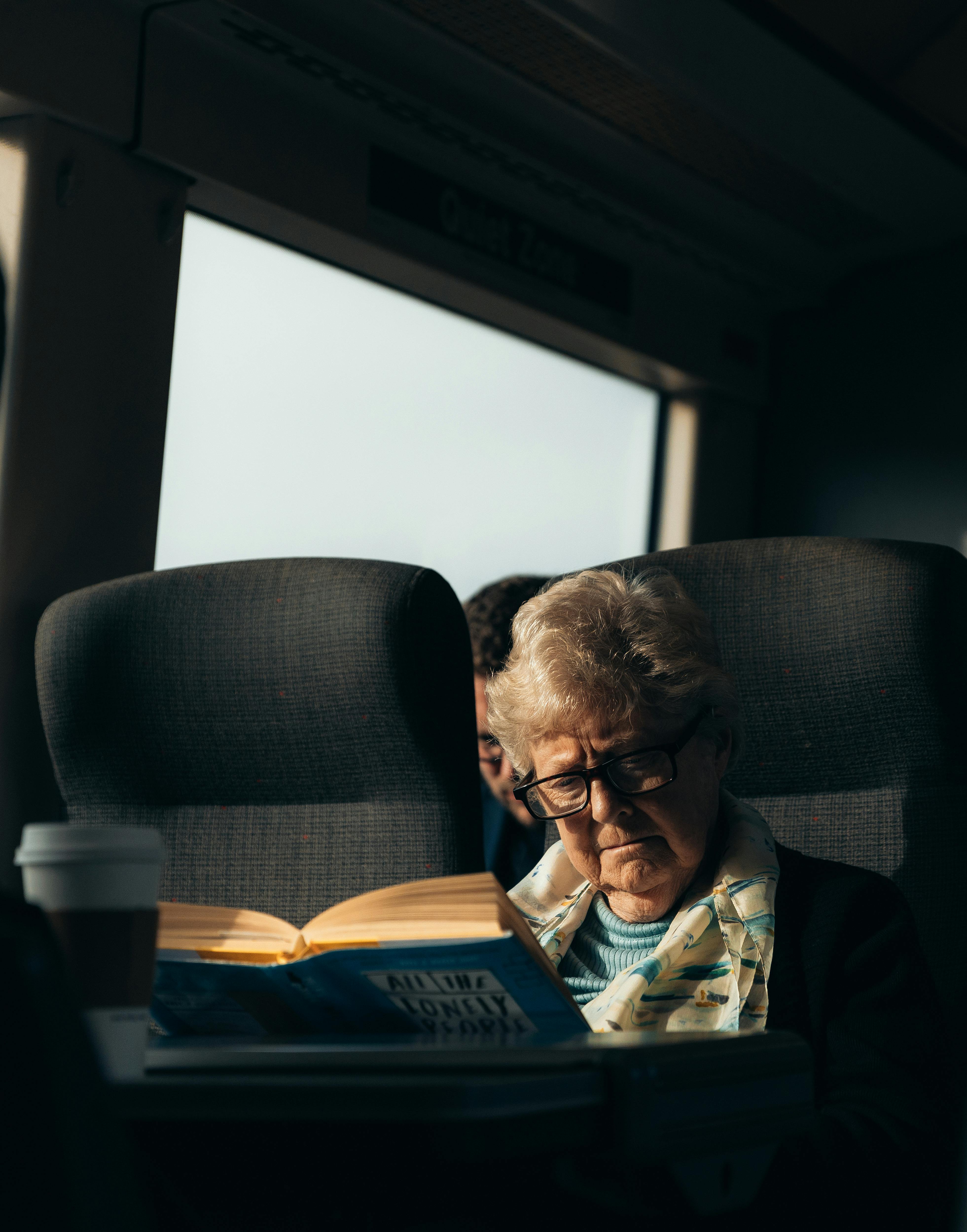 An elderly woman reading a book while traveling by train | Source: Pexels