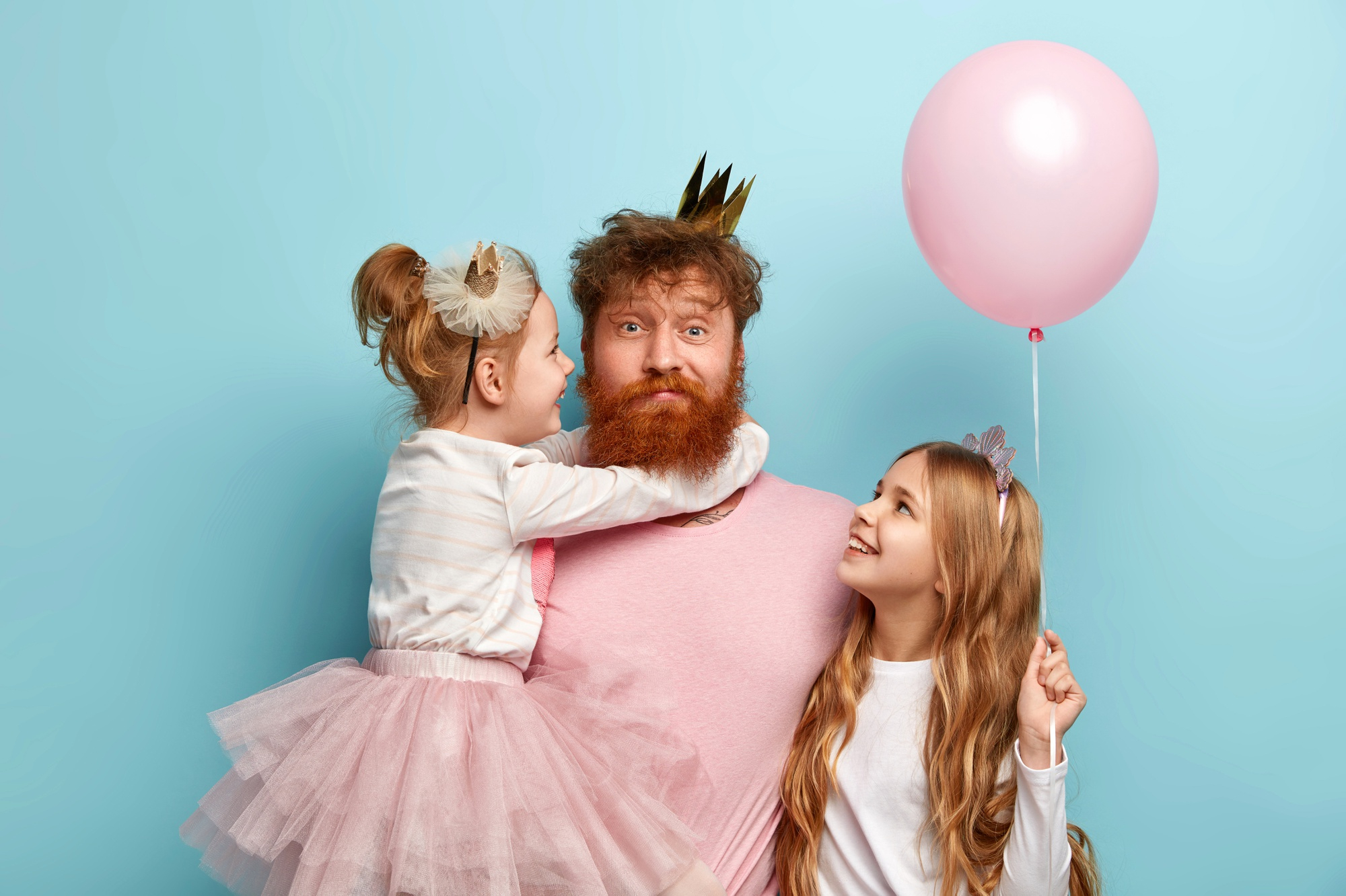 A father dressed in a tiara with his girls | Source: Freepik