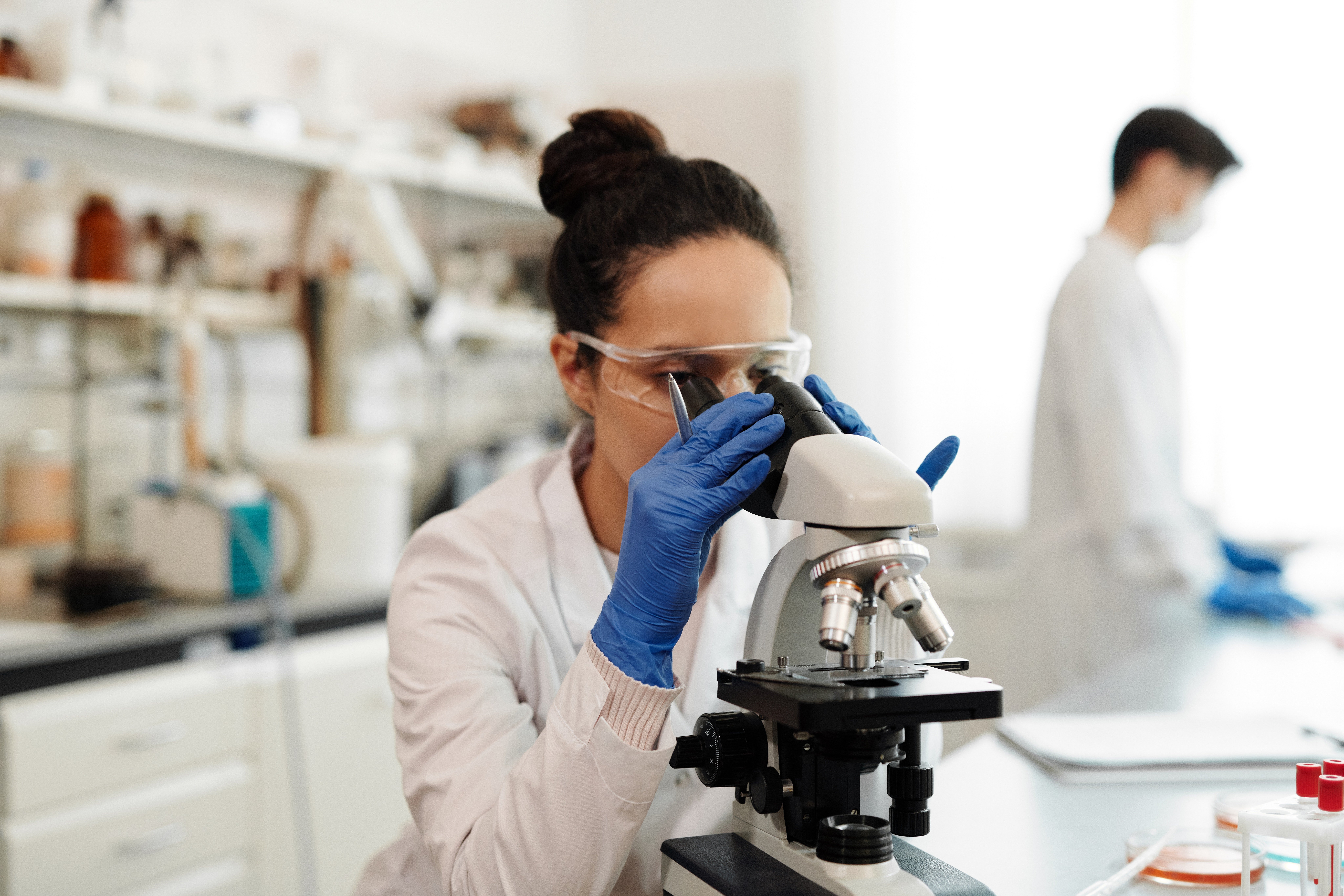 Una profesional observa una muestra en el microscopio en un laboratorio. | Foto: Pexels
