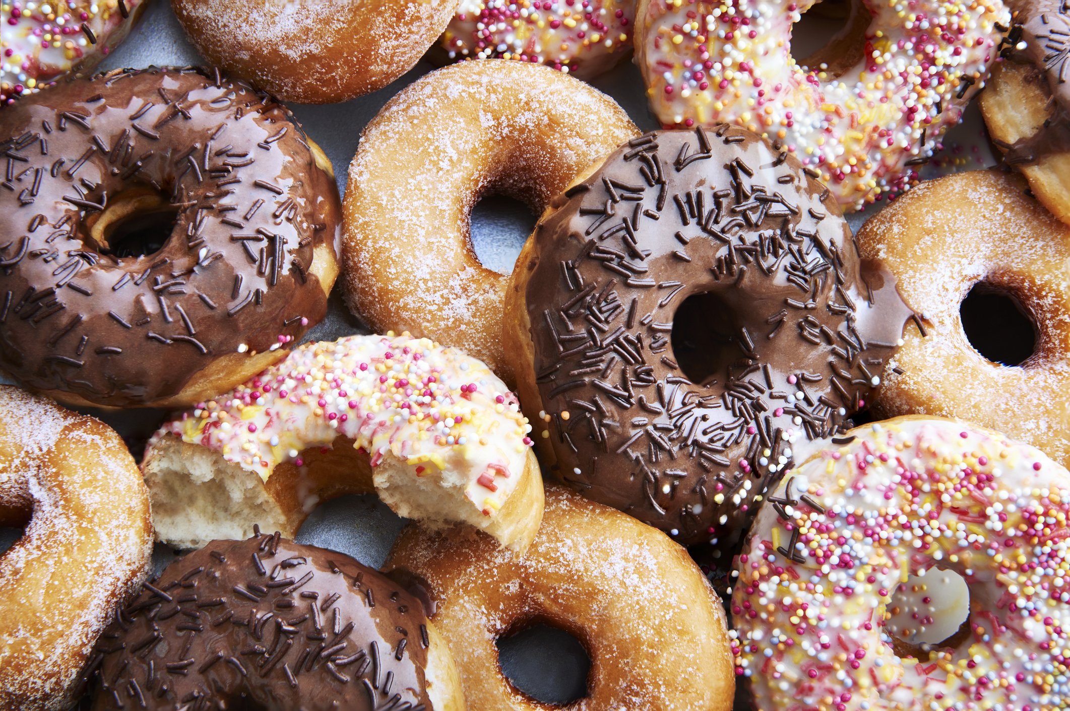 Ring doughnuts covered in icing and sprinkes | Photo: Getty Images