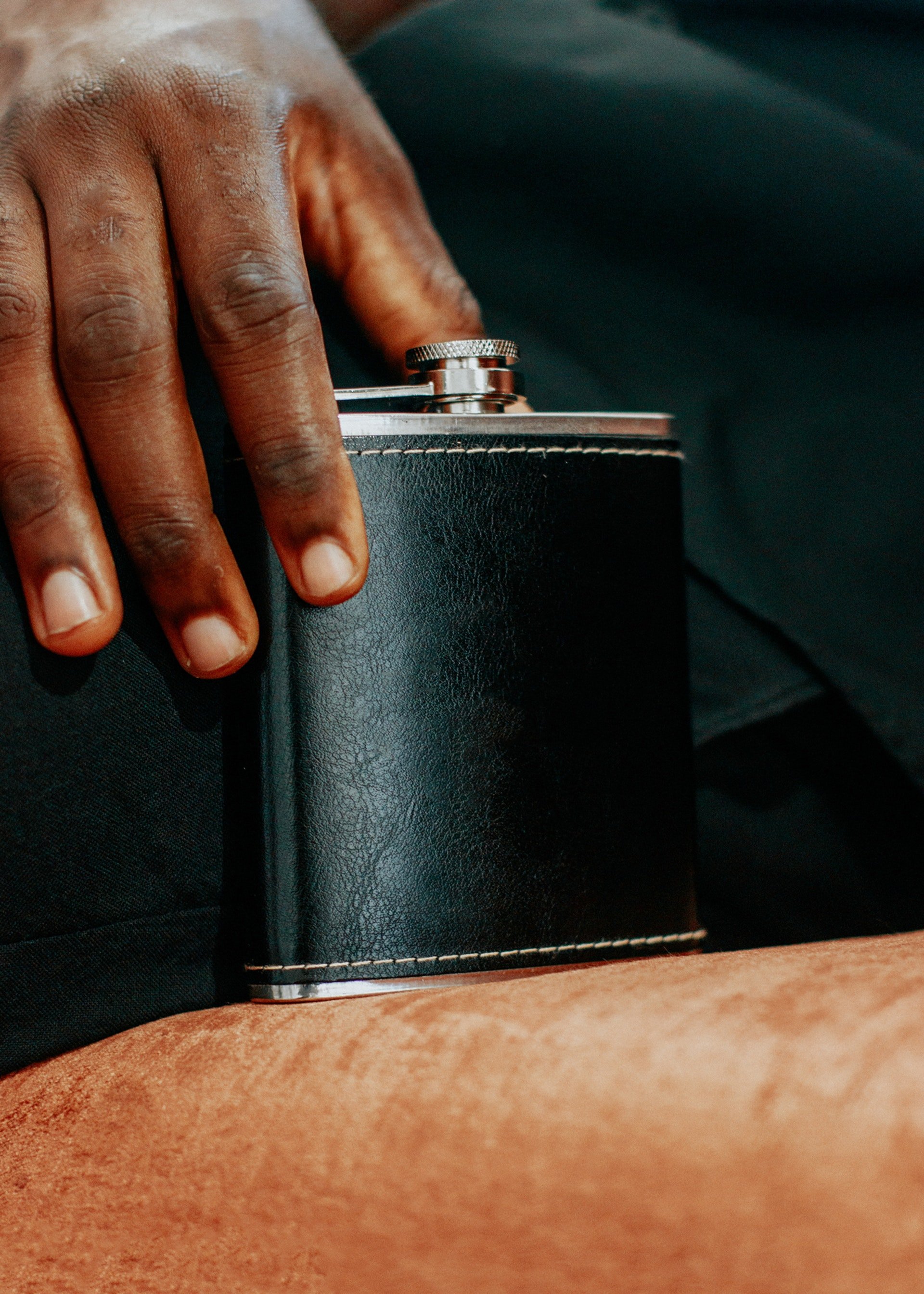 A person holding a black leather flask | Source: Pexels