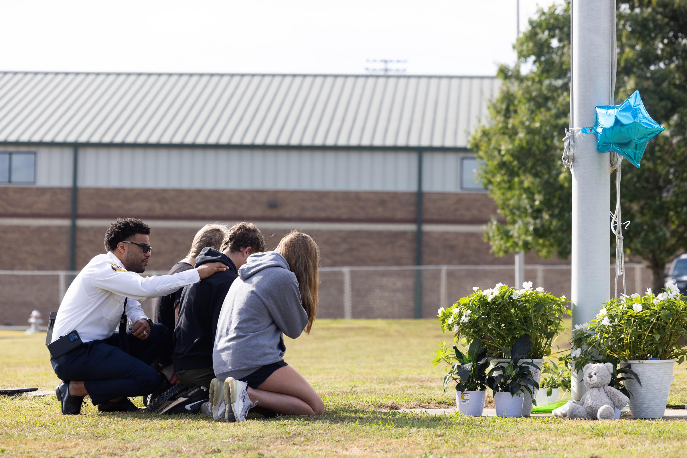 State of Georgia Chaplain Ronald Clark consoling students kneeling down in front of a memorial that was made at Apalachee High School in Winder, Georgia on September 5, 2024 | Source: Getty Images