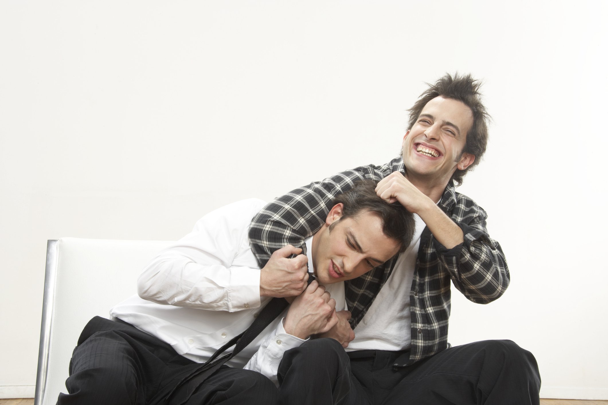 Twin brothers seated on a couch laugh out loud about something hilarious | Photo: Getty Images 
