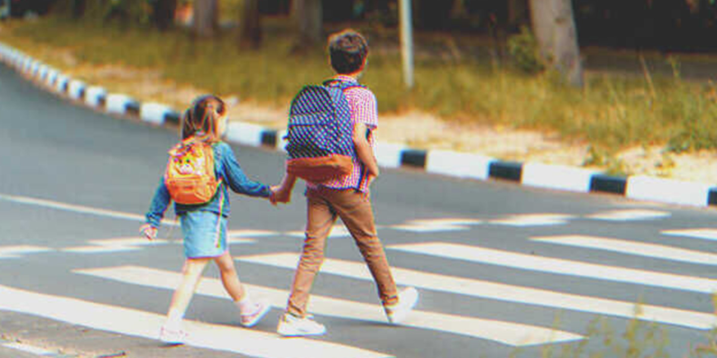 A boy walking down the street holding the hand of a little girl | Source: Shutterstock
