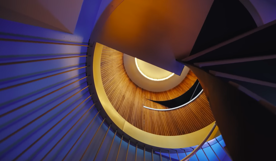 The custom staircase is one of the home's most dramatic architectural moments — and one of Christopher's personal favorites. Its twisting metal structure turns a practical connection between two floors into a piece of sculpture. | Source: YouTube/Architectural Digest