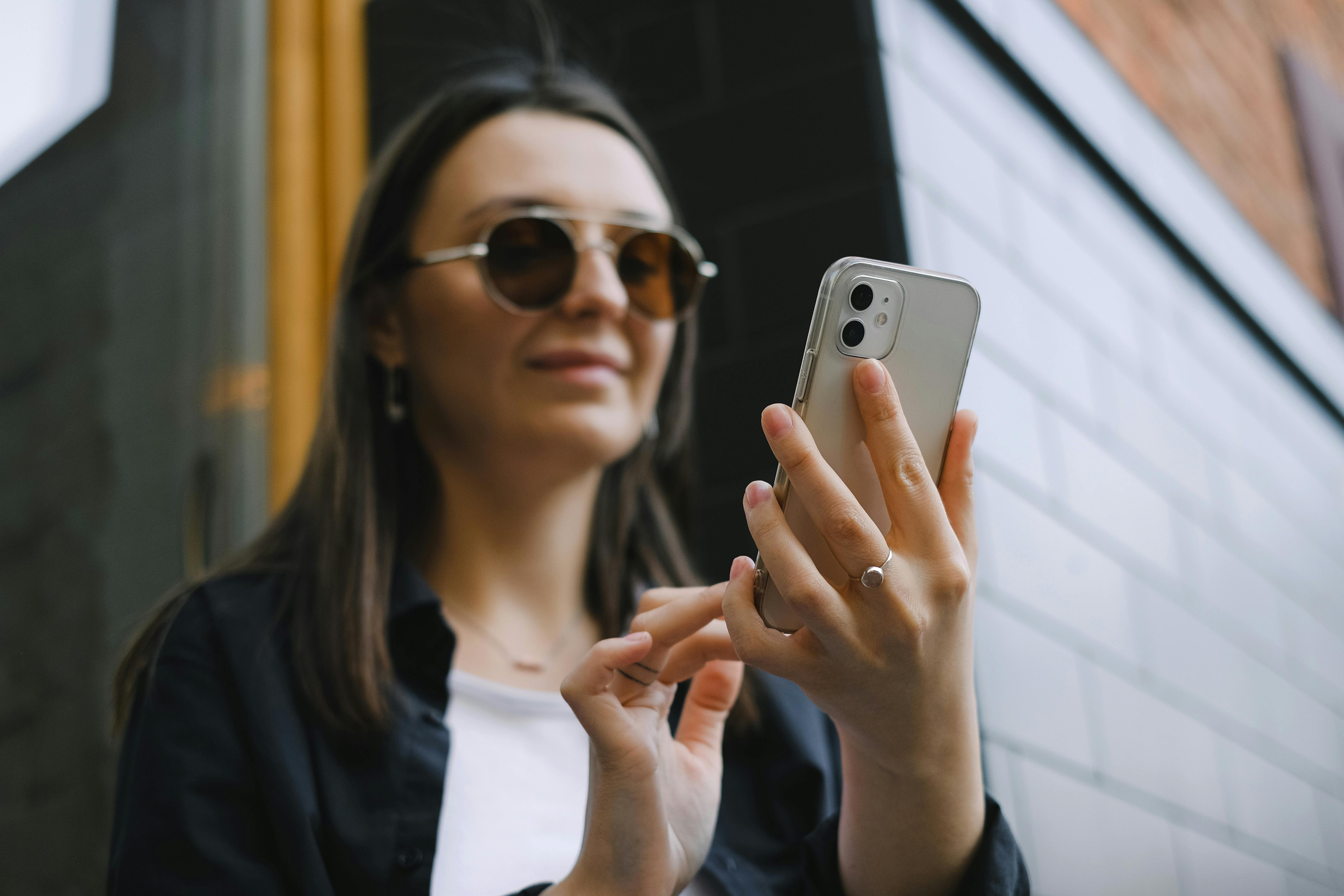 A smiling woman typing on her phone | Source: Pexels