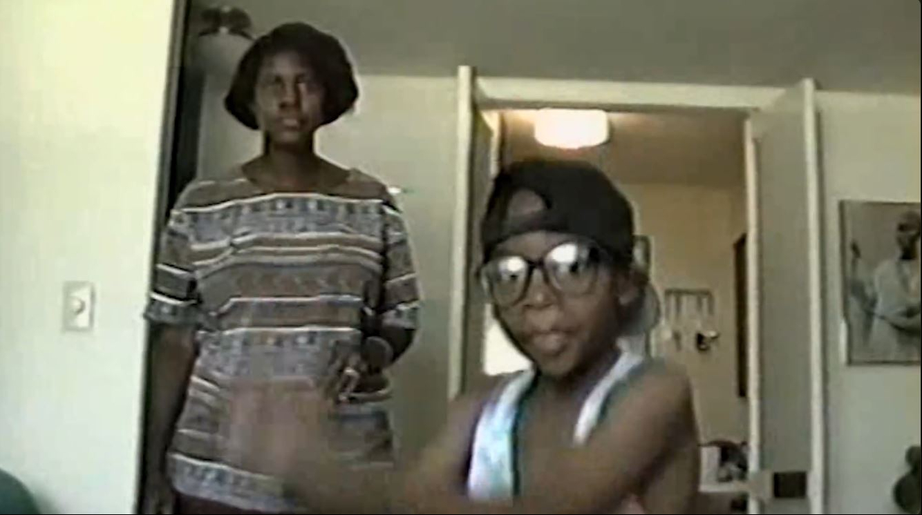 Peachy Wimbush-Polk stands behind a young Wiz Khalifa in a home video shared in Episode 1 of "Behind the Cam," published on February 24, 2021. | Source: YouTube/Wiz Khalifa
