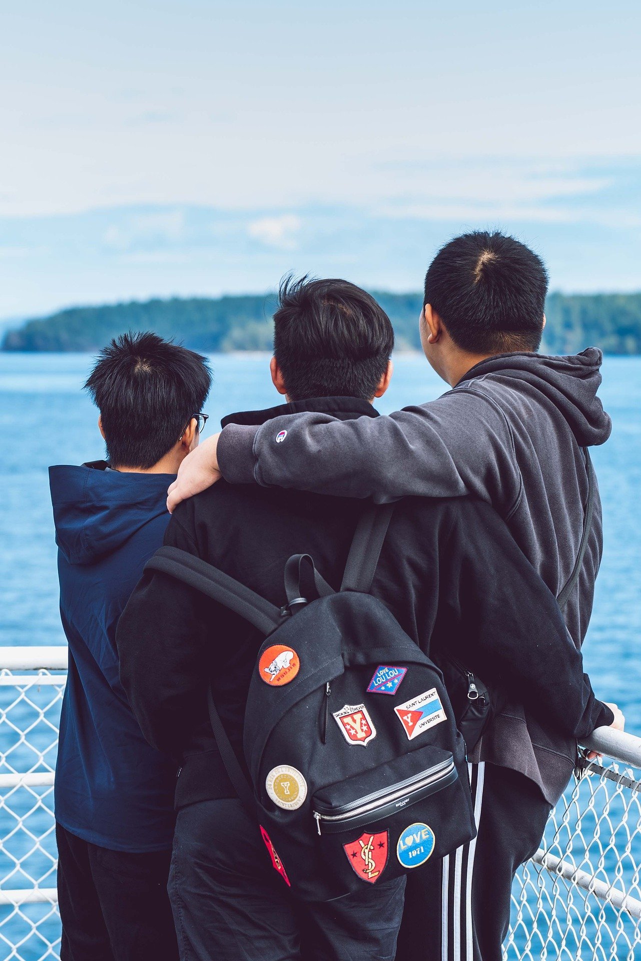 Three boys embracing while looking out to sea | Photo: Pixabay/Vlad Vasnetsov