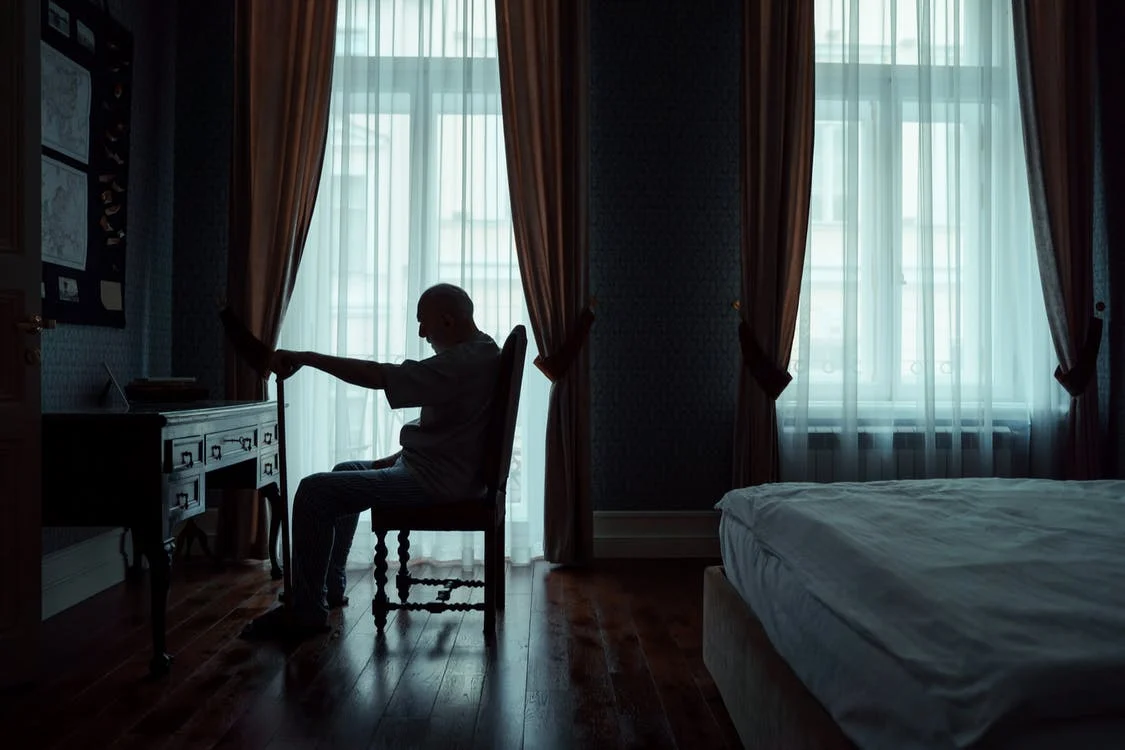 Hombre mayor sentado en habitación oscura. | Foto: Pexels