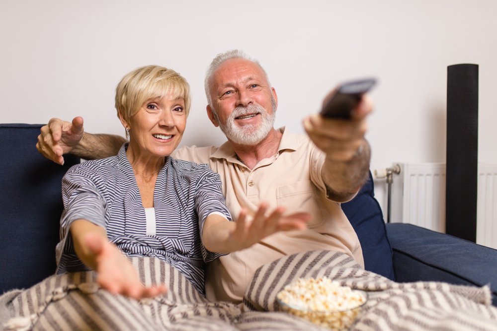 Man watching TV next to exasperated wife | Shutterstock