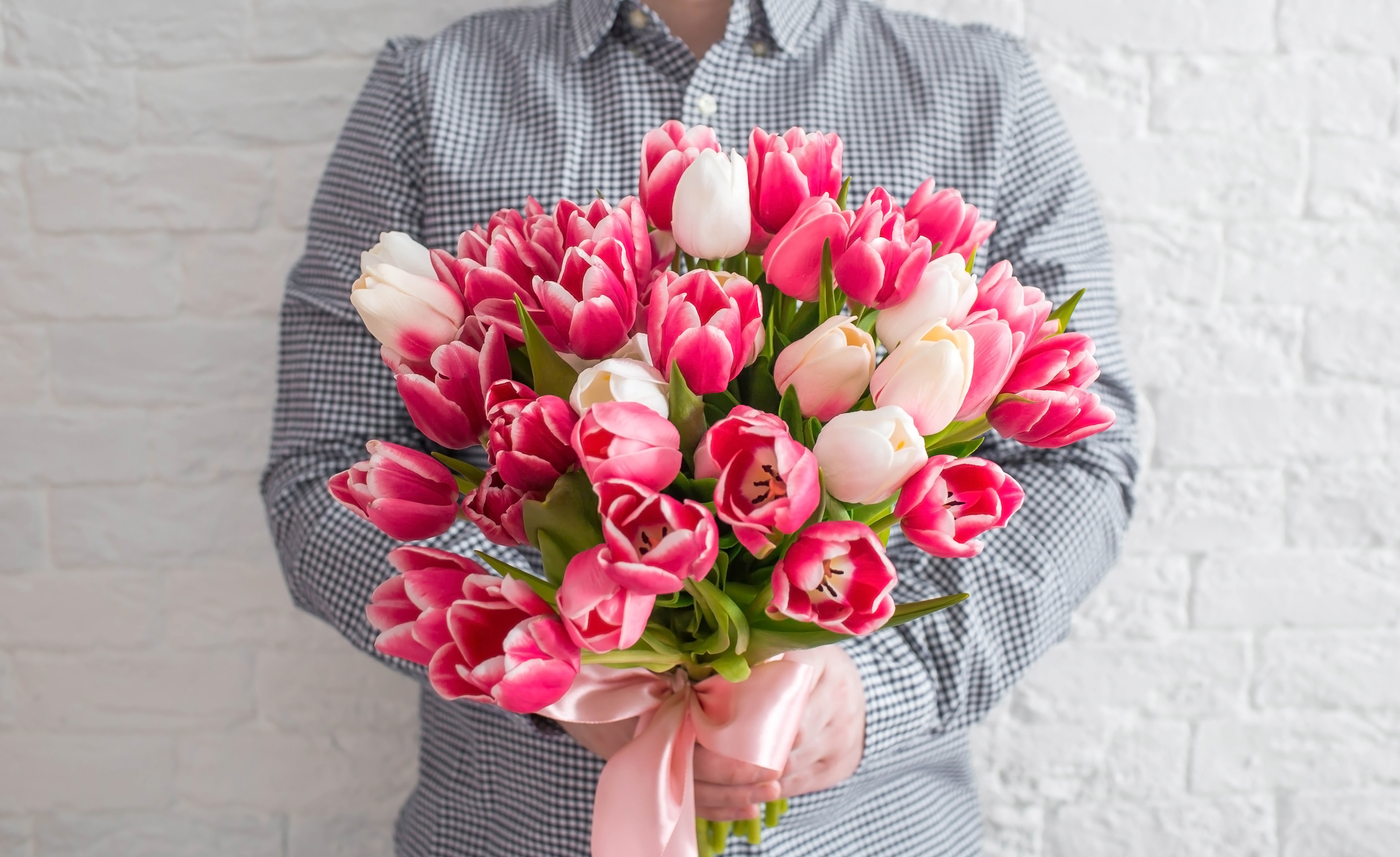 A man holding a bouquet of white and pink tulips | Source: Shutterstock