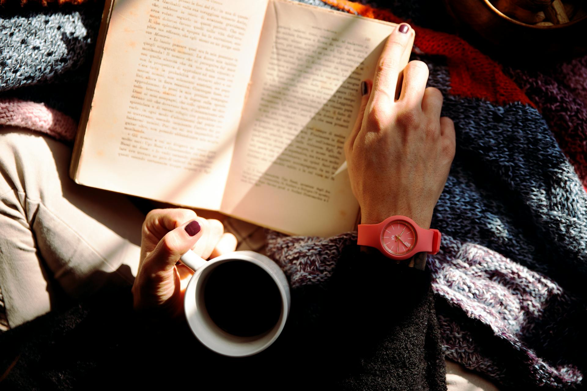 Person reading a book and holding a mug | Source: Pexels
