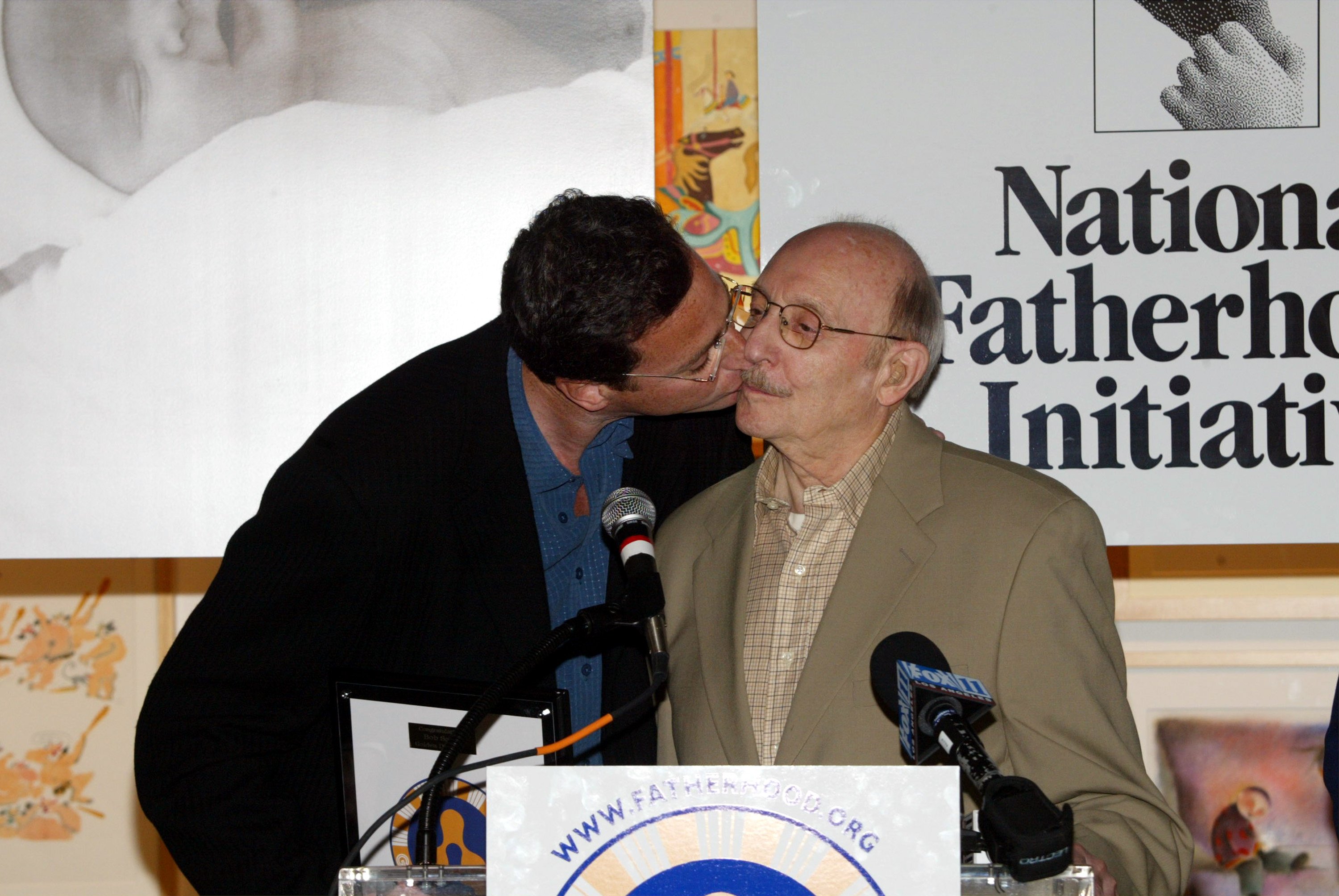 Bob Saget kisses his dad Benjamin Saget during a press conference for the National Fatherhood Initiative "Golden Dads" campaign on June 4, 2003, in Los Angeles, California. | Source: Getty Images