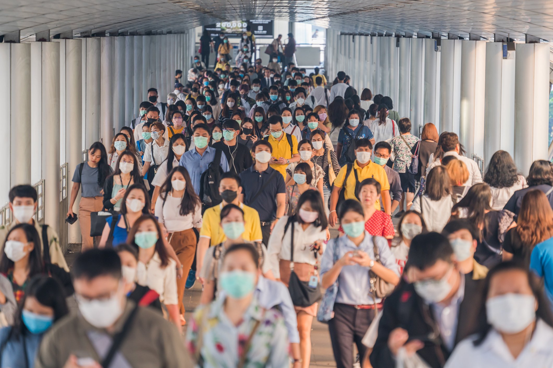 Massen von Asiaten, die Gesichtsschutz tragen, während sie zur Hauptverkehrszeit am Morgen zu ihrem Arbeitsplatz in Bangkok gehen | Quelle: Getty Images