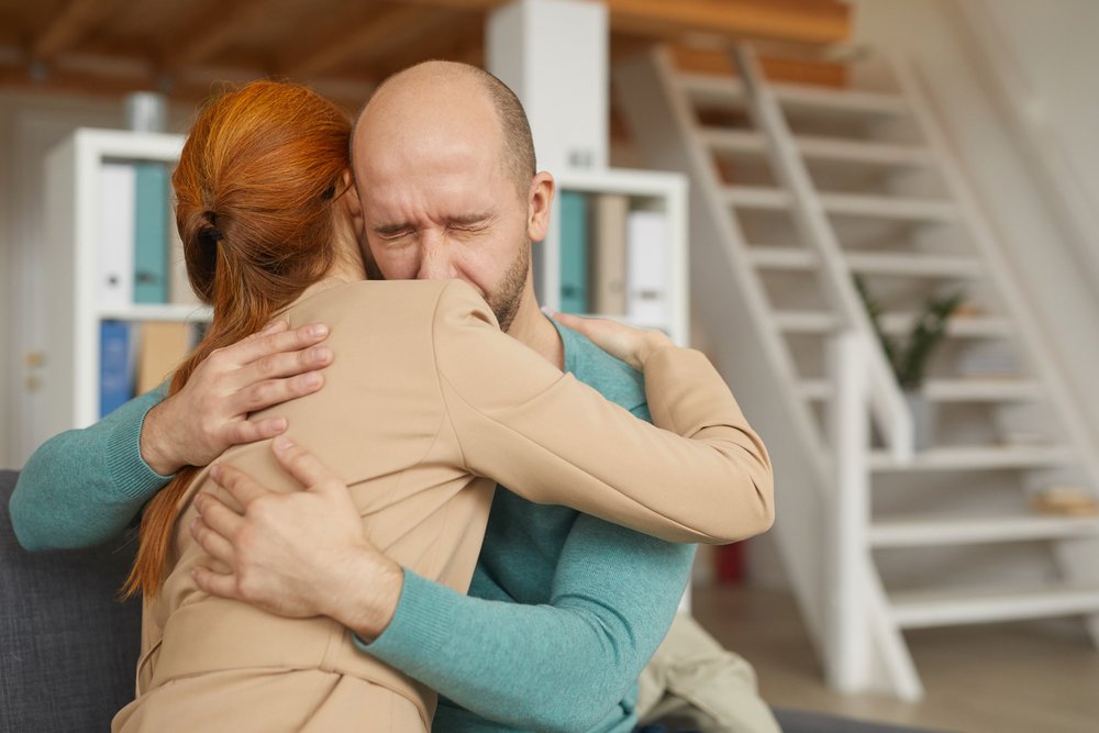 Hombre abrazando a su madre mientras llora. | Foto: Shutterstock