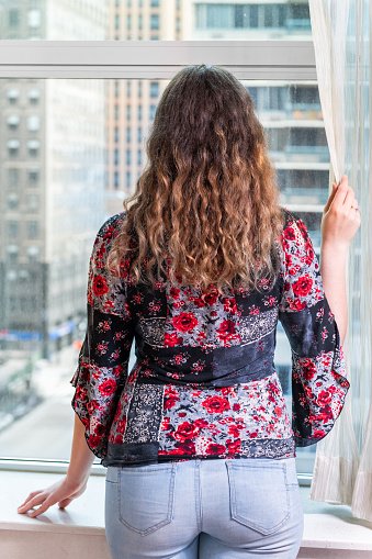 Une jeune femme debout regardant sur la fenêtre. | Photo : Getty Images