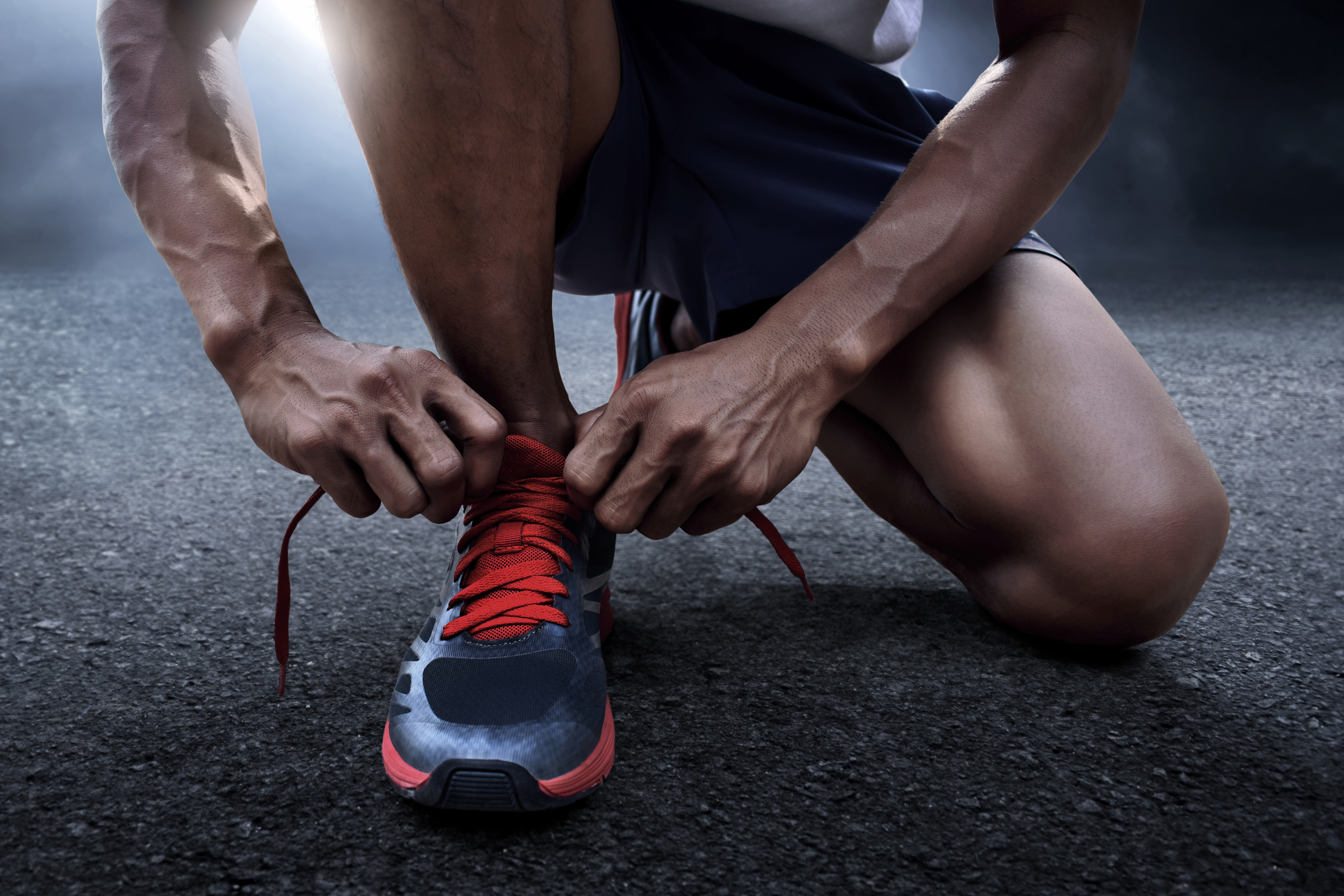 A man tying his shoe lace as he prepares to run | Source: Shutterstock