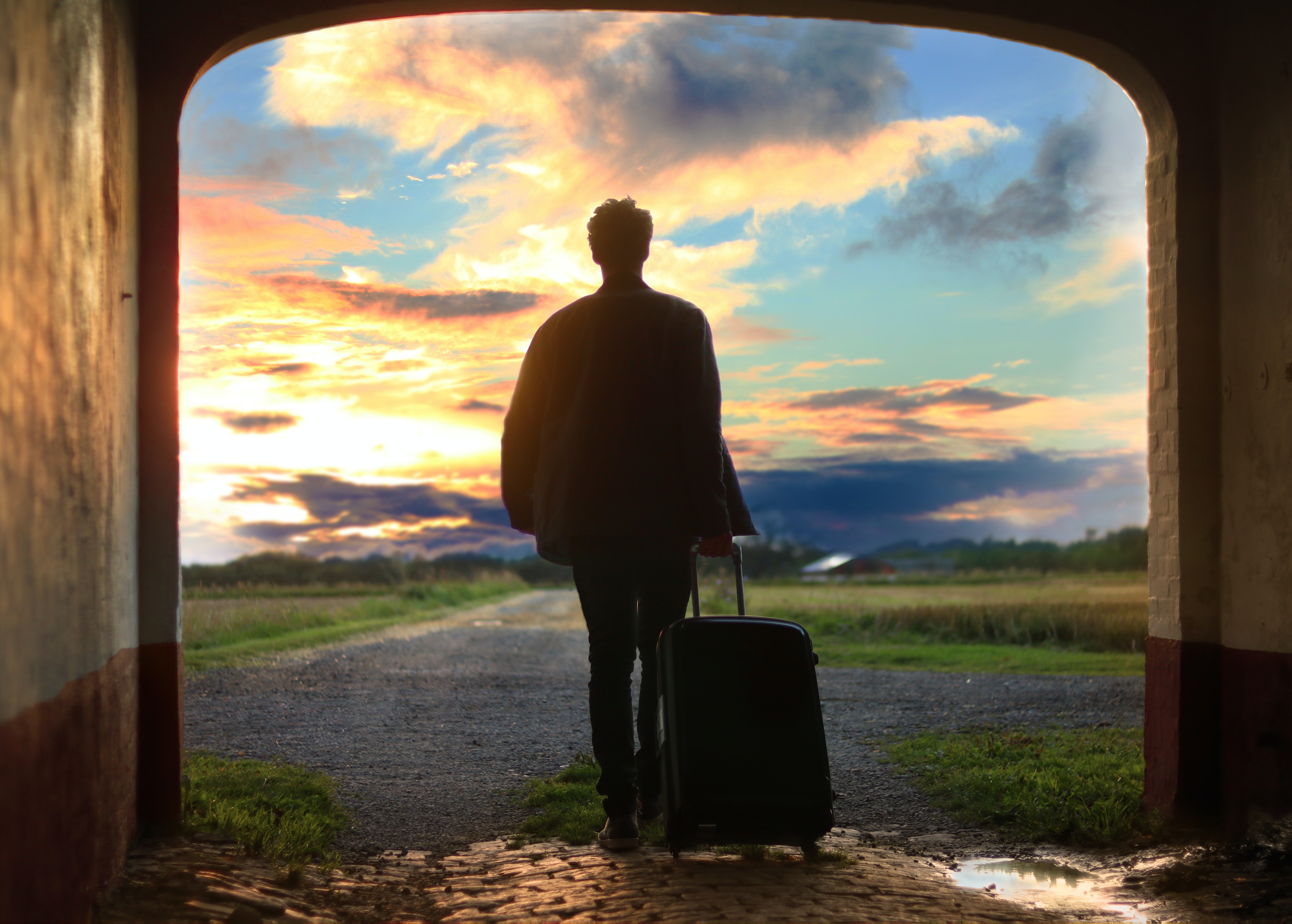 Man walking with his luggage in tow | Source: Unsplash/ Mantas Hesthaven