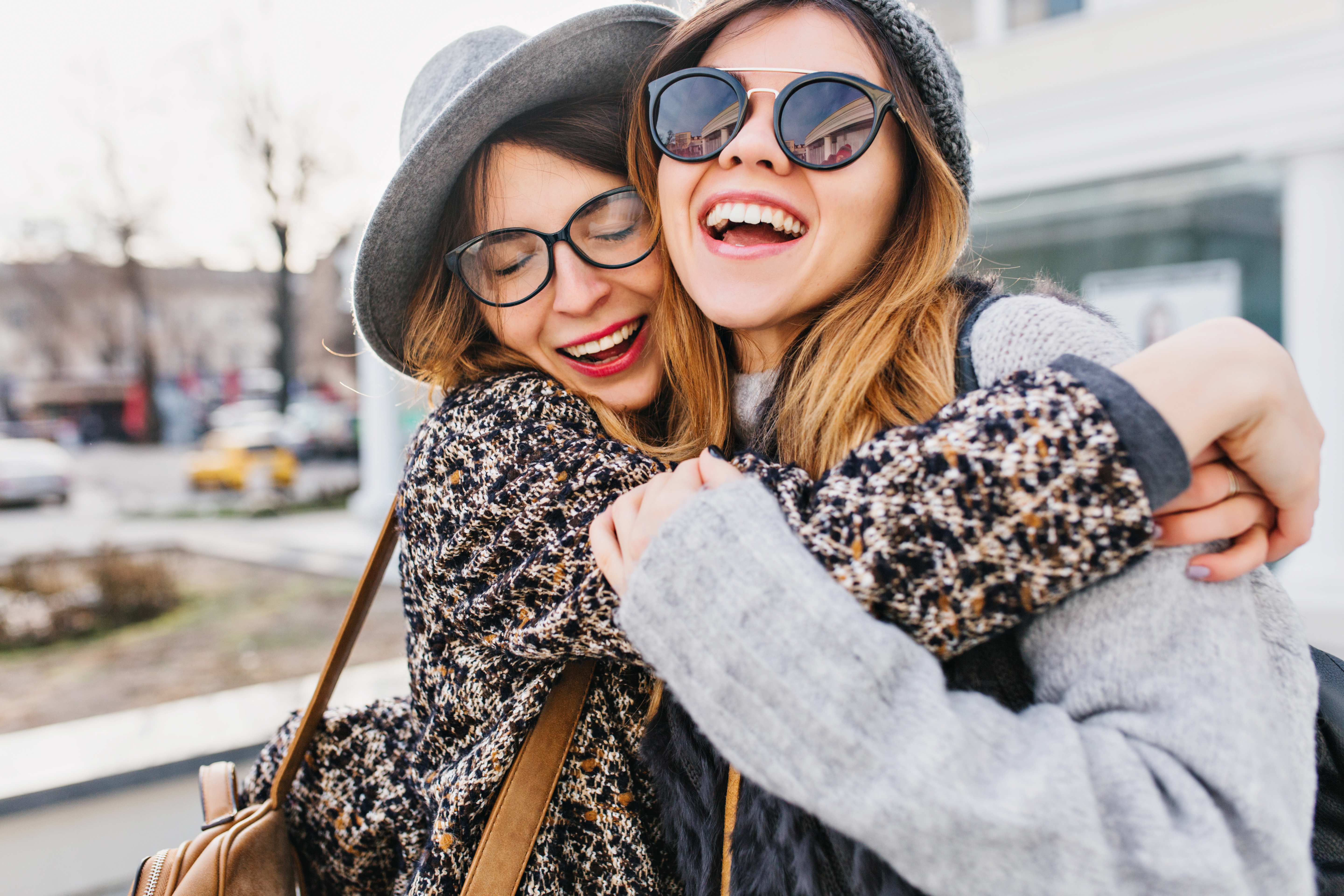 Two young woman laughing and hugging | Source: Shutterstock