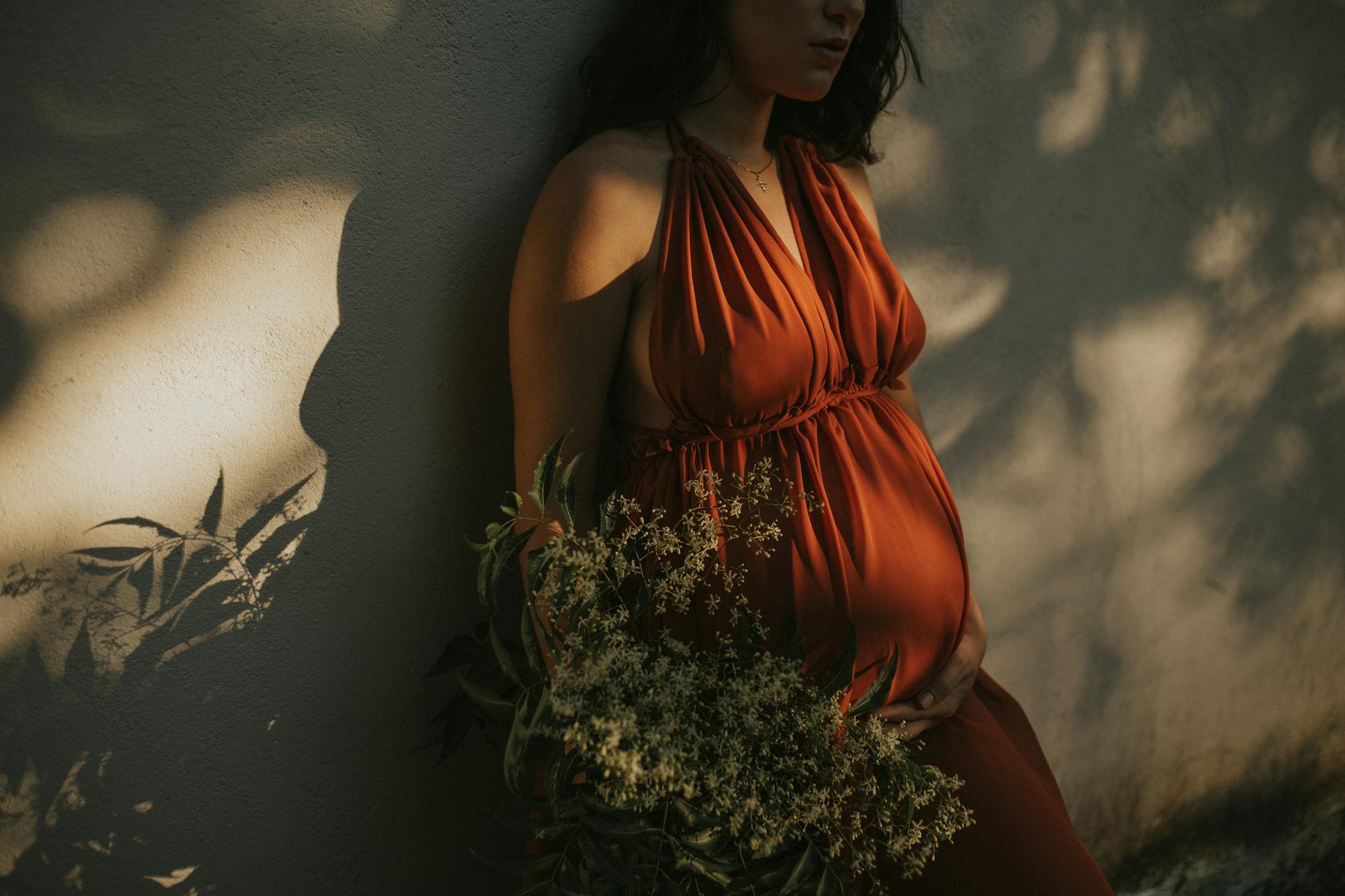 A pregnant woman standing against a wall | Source: Pexels