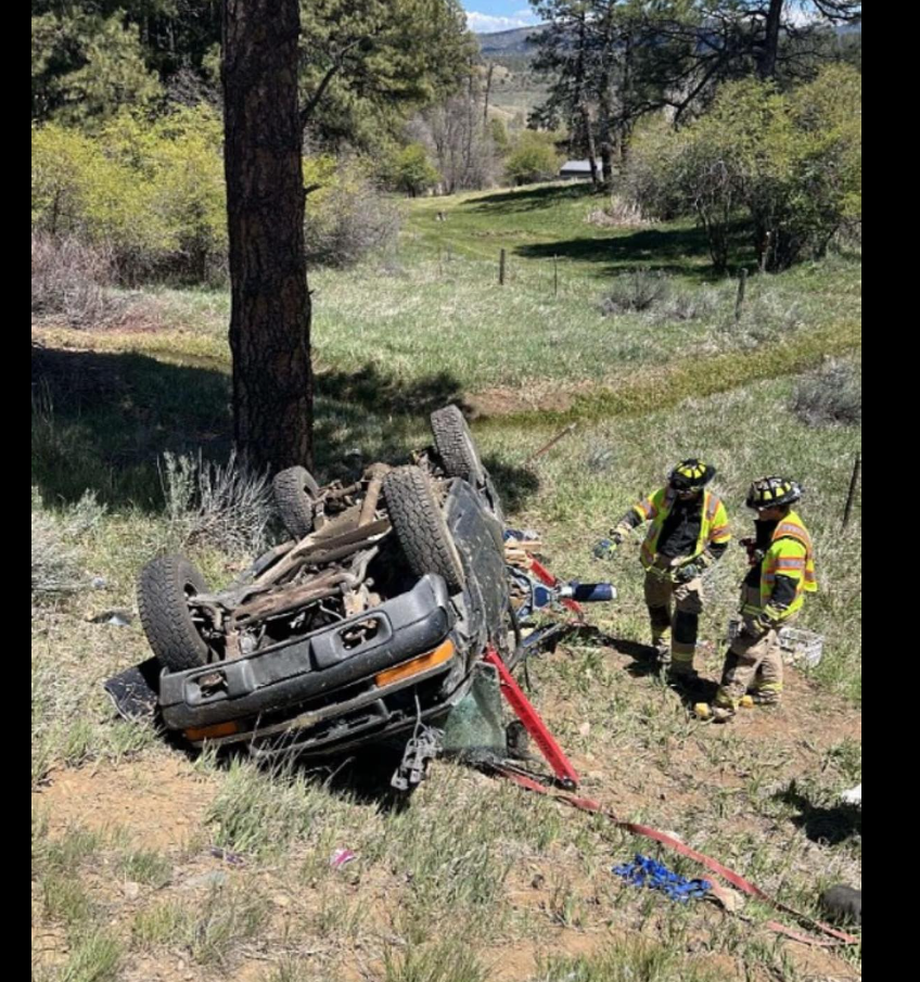 The blue Chevrolet S-10 pickup truck sits overturned at the bottom of a grassy embankment as emergency responders stand nearby assessing the crash scene. | Source: Facebook/Jade Charde’