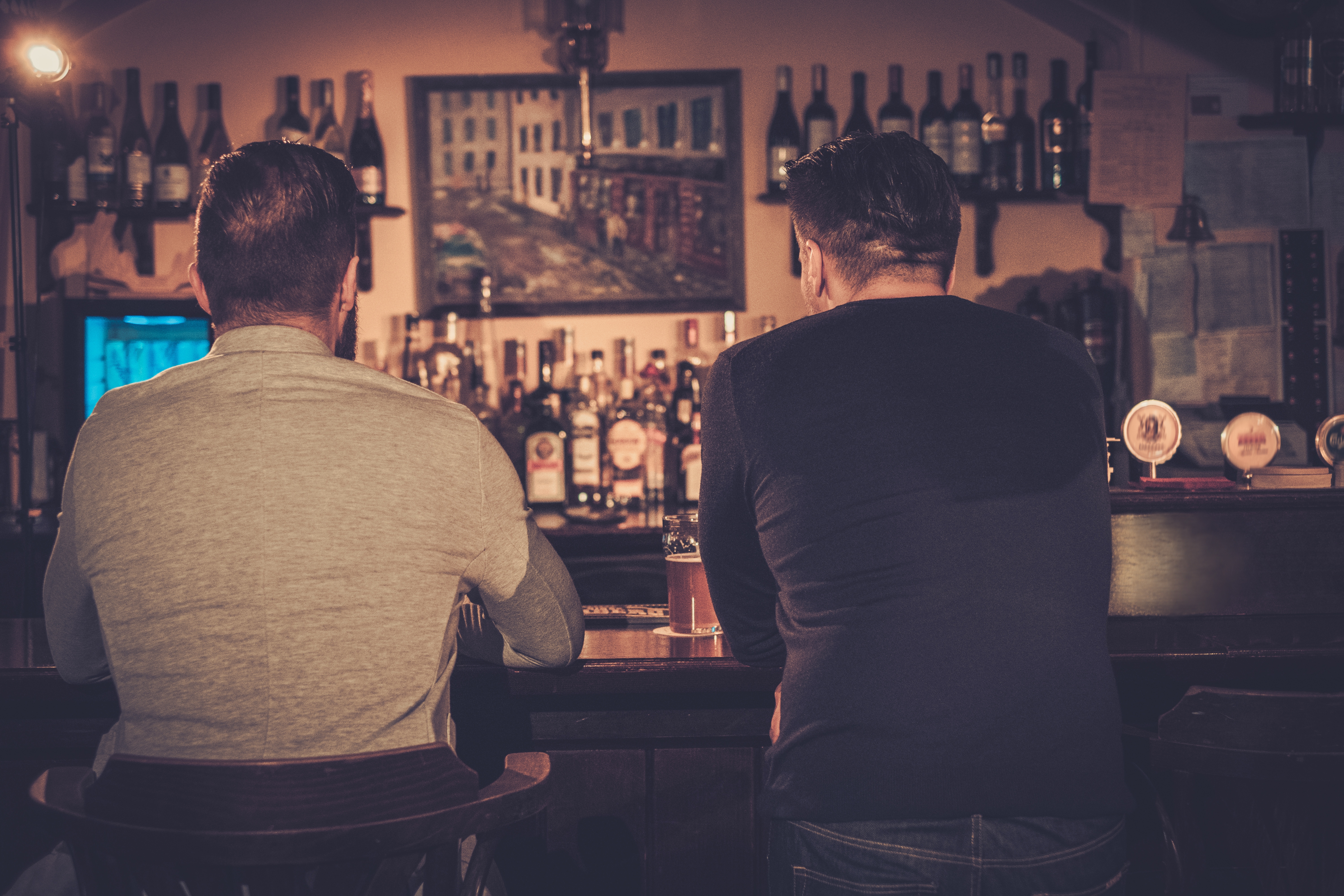 Cheerful old friends at bar counter in pub. | Source: Shutterstock