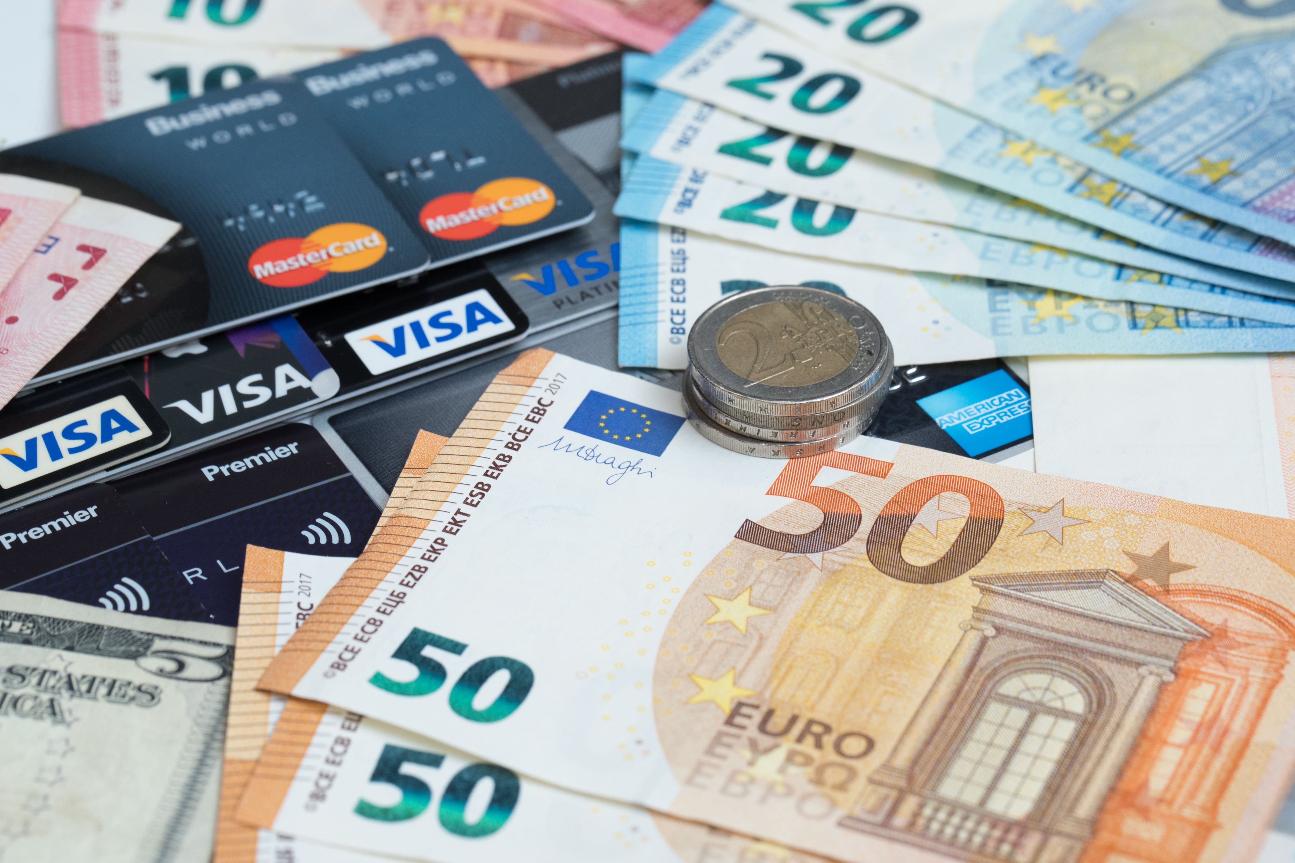 Euro coins and bills and several VISA credit cards | Photo: Getty Images