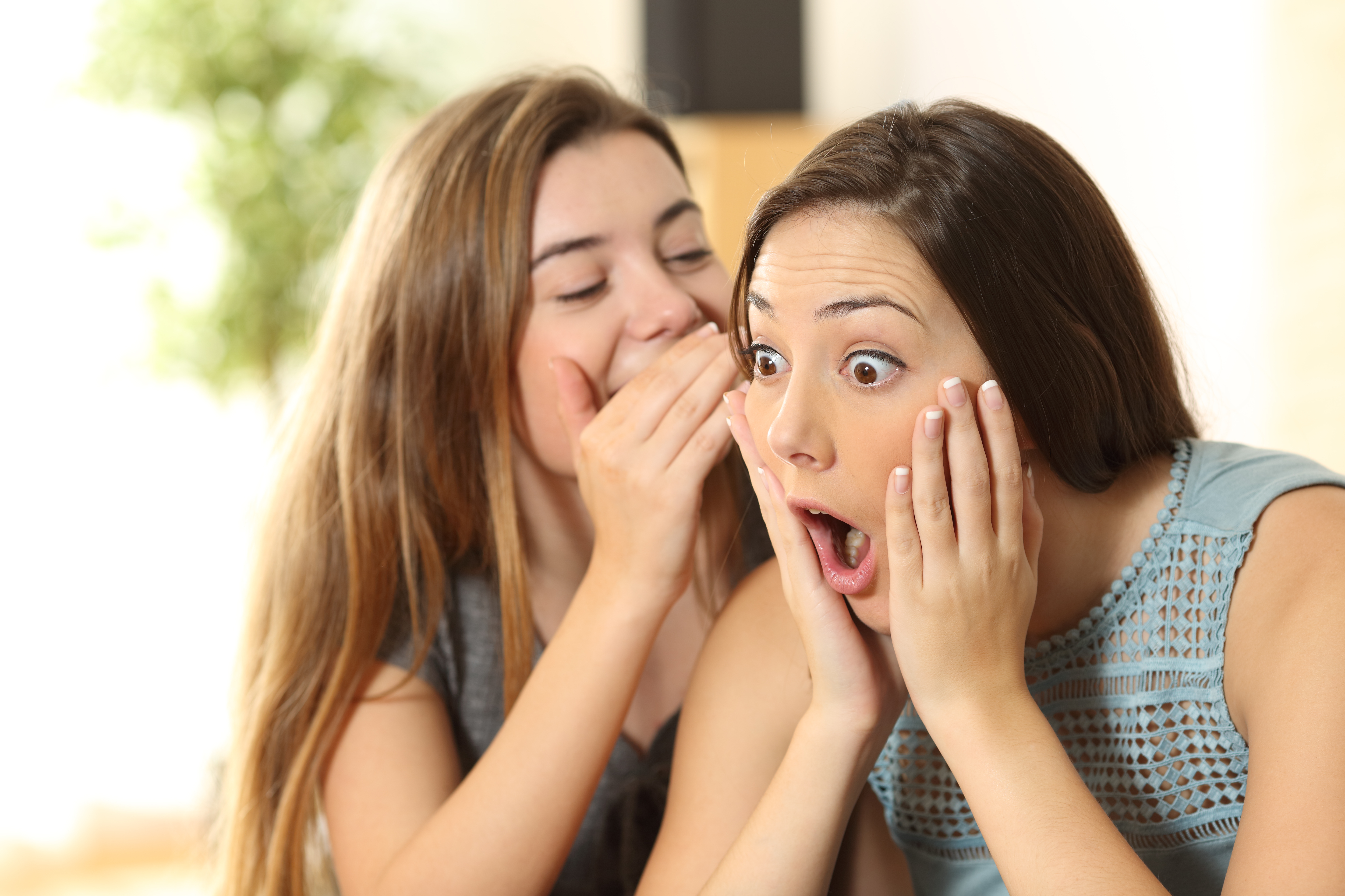 Two women telling each other secrets | Source: Shutterstock