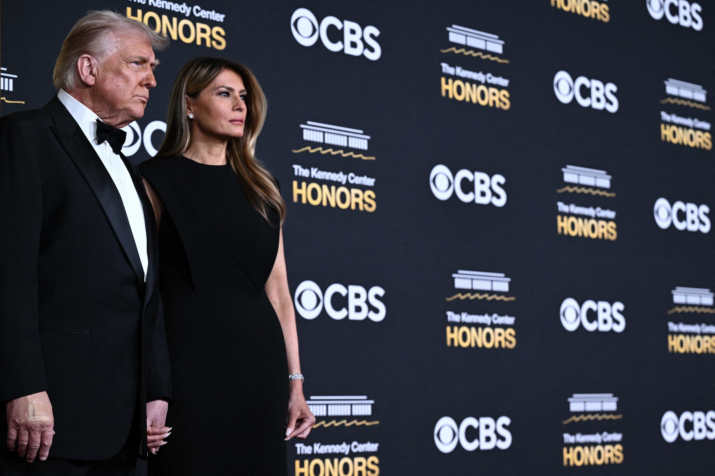 A side-view profile showing Donald and Melania Trump posing on the red carpet, with Donald's band-aid slightly visible. | Source: Getty Images