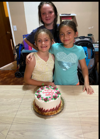 Jordan roe and her cousins, Laila, and Brylee, photograph in front of a cake, dated June 24 2025 | Source: Gofundme