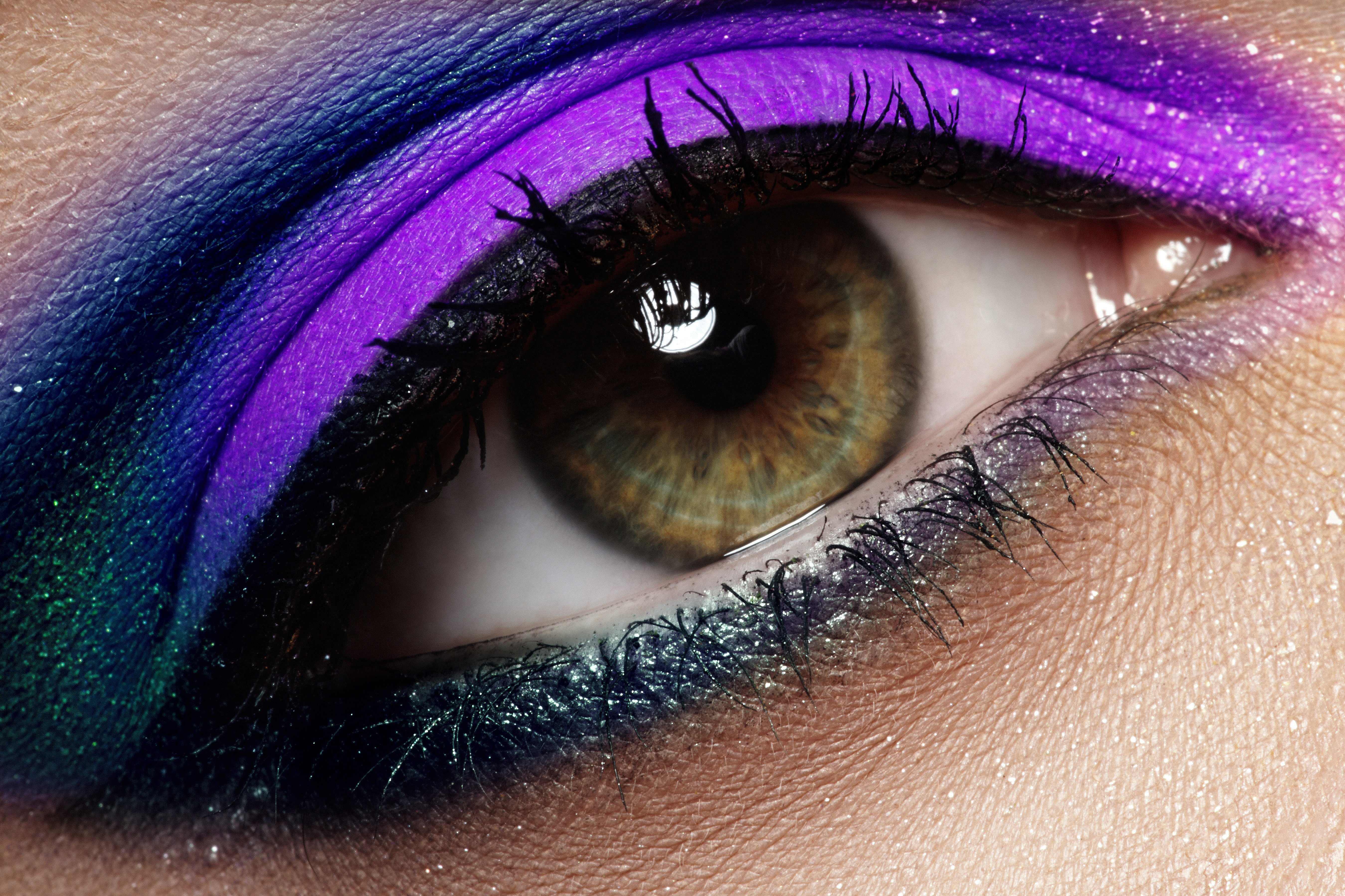 A macro shot of  a woman with green eyes wearing dark purple eyeshadow colors make-up, creating a sultry evening look | Source: Shutterstock
