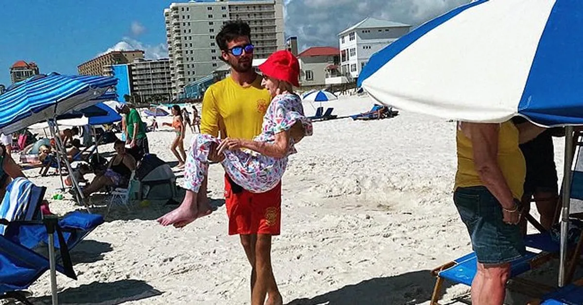 A picture of a lifeguard at Orange Beach carrying Dottie Schneider | Photo: Facebook.com/OrangeBeachSurfRescue