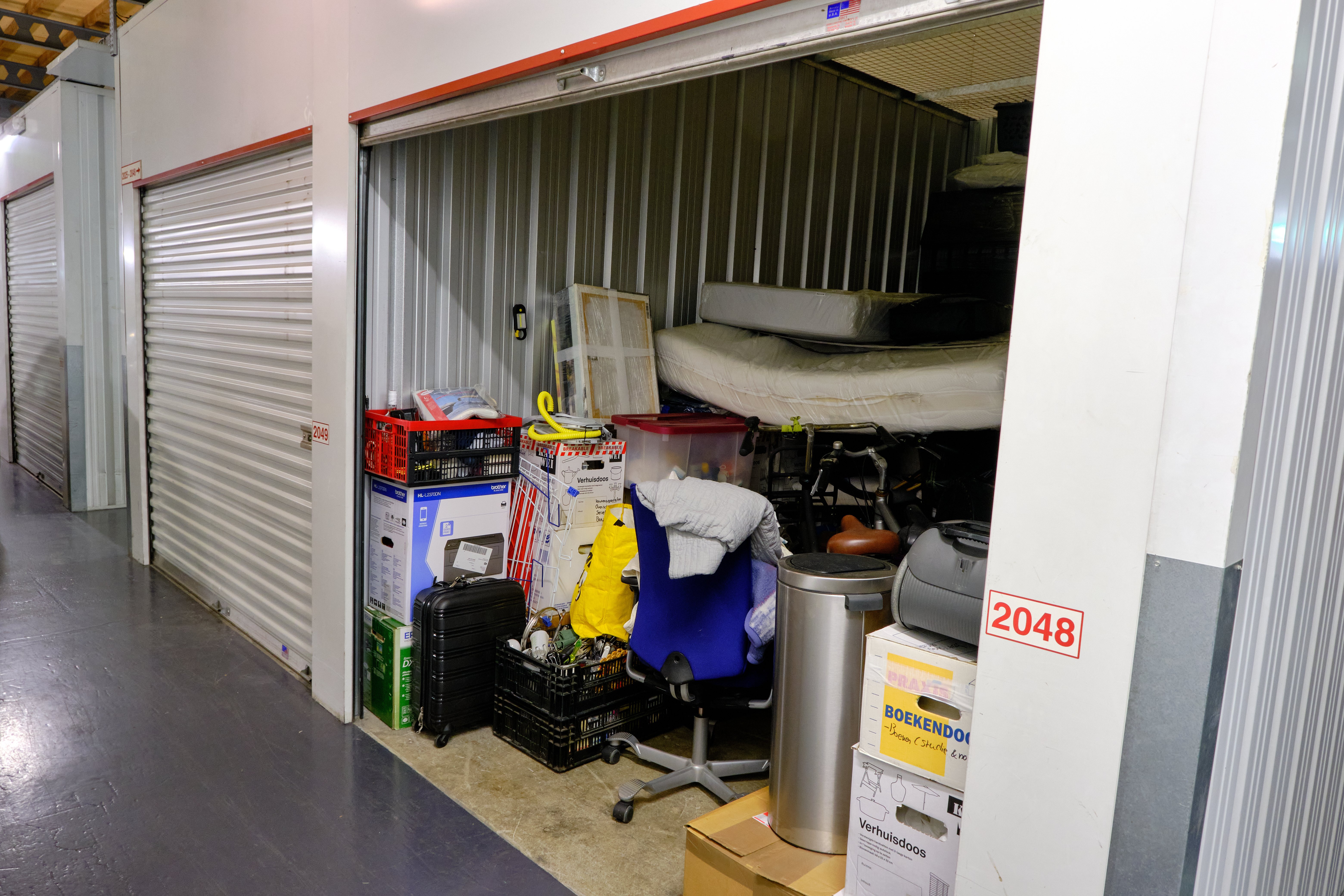 An indoor storage unit with open door and household goods inside. | Source: shutterstock