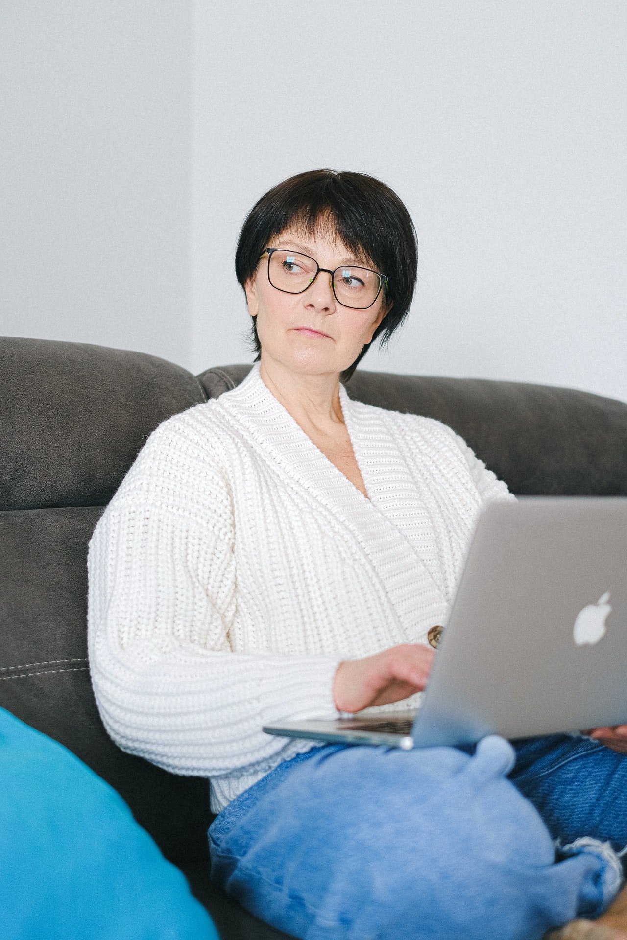 Una mujer mayor con rostro serio usando una computadora portátil. | Foto: Pexels