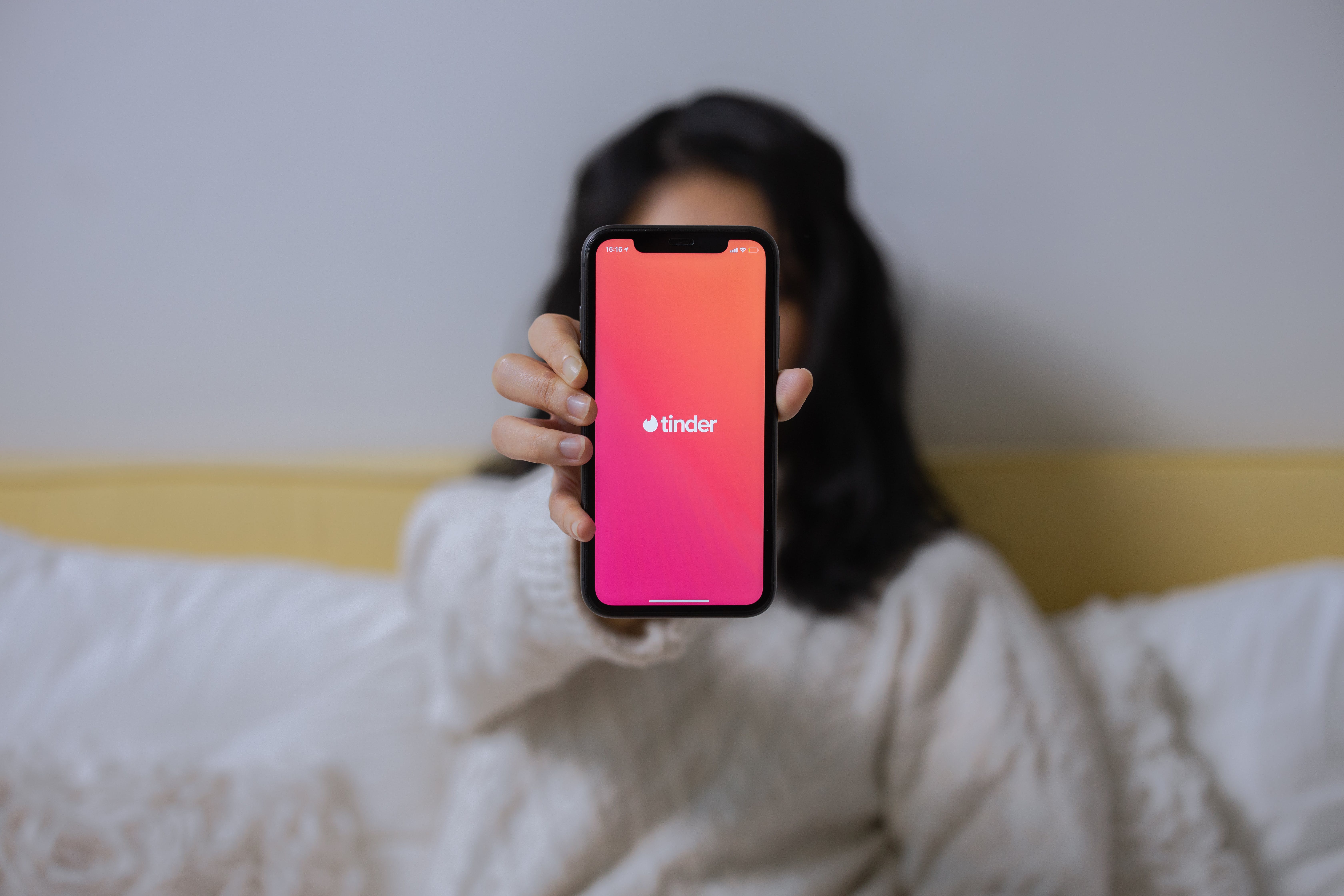 A woman holding up a phone showing a dating app | Source: Pexels